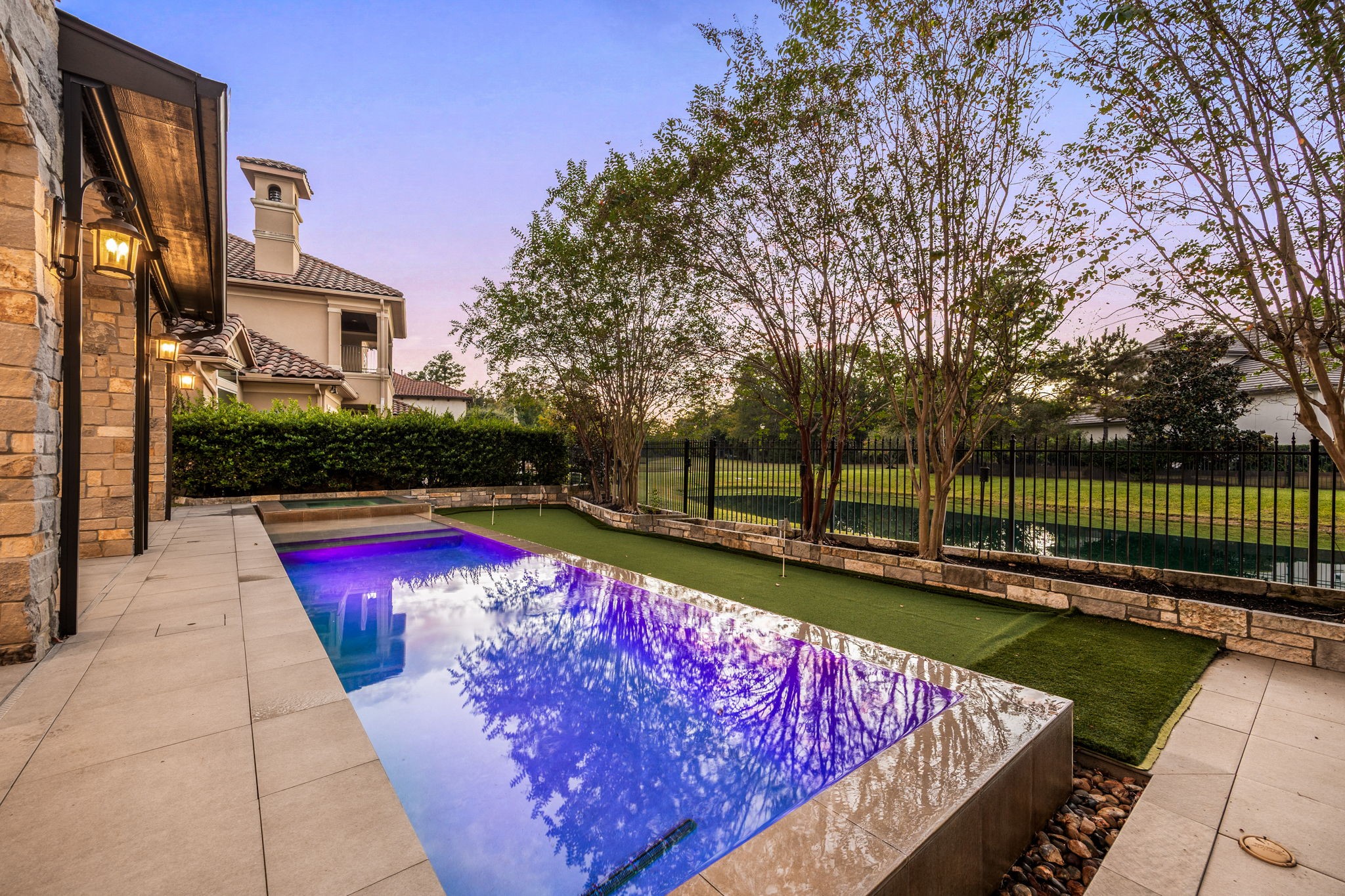 Designed for effortless outdoor enjoyment, the private pool and spa are framed by elegant stone coping, expansive paved decking, and lush landscaping. The adjacent putting green and tranquil lake views create a serene backyard retreat, perfect for leisurely afternoons and relaxing evenings at home.