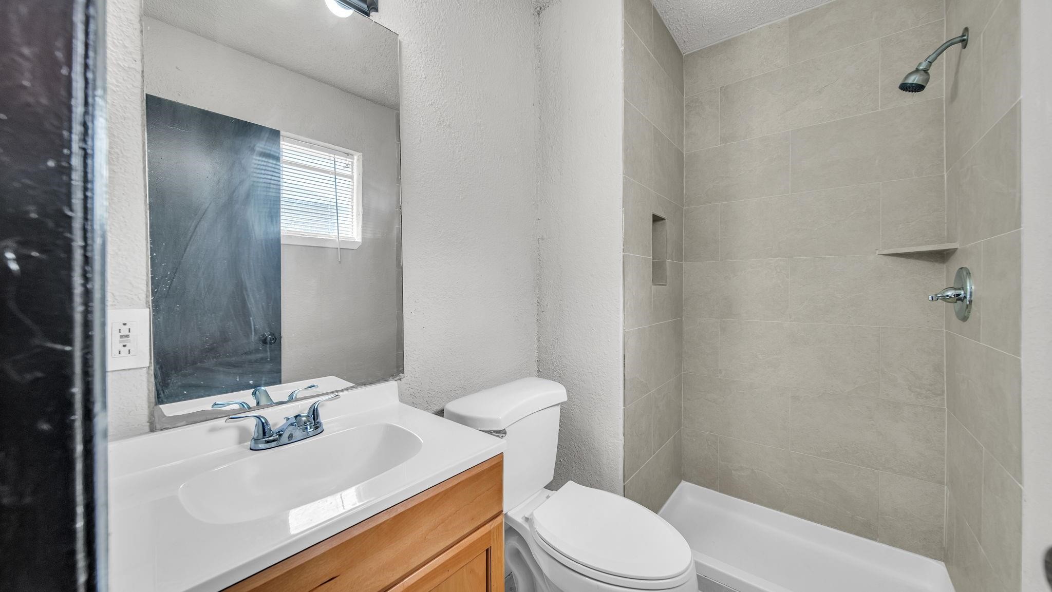The en suite bath offers an elegant combination of style and functionality, featuring a beautifully appointed shower with 12 x 24 tile extending to the ceiling, a built-in shampoo niche, and a cultured marble vanity. Sophisticated finishes create a polished, inviting space for daily routines.