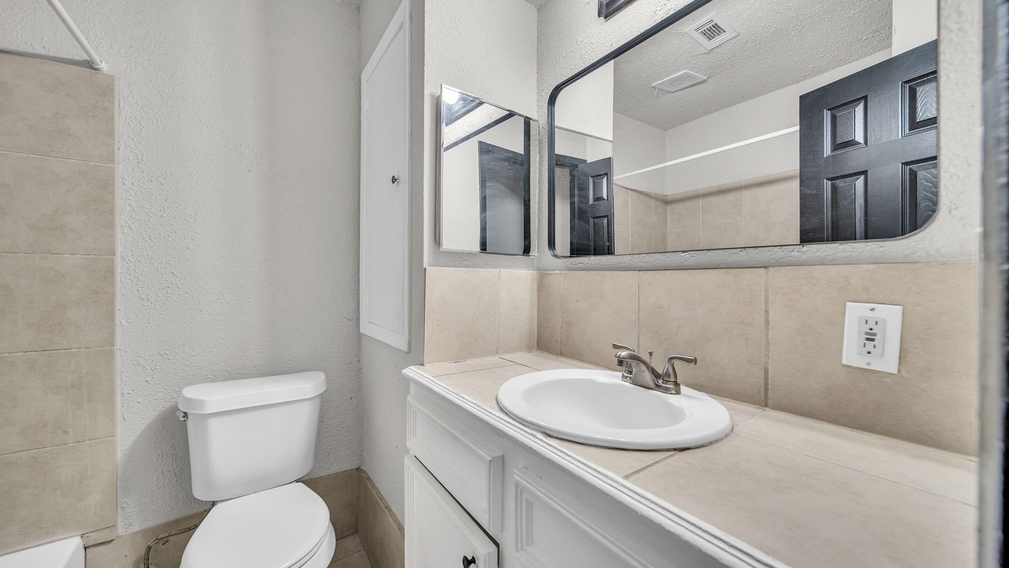 The beautifully appointed secondary bathroom features a tile countertop and a tub/shower combination accented by a coordinating tile surround, offering a polished blend of style, comfort and everyday convenience for family and guests alike.
