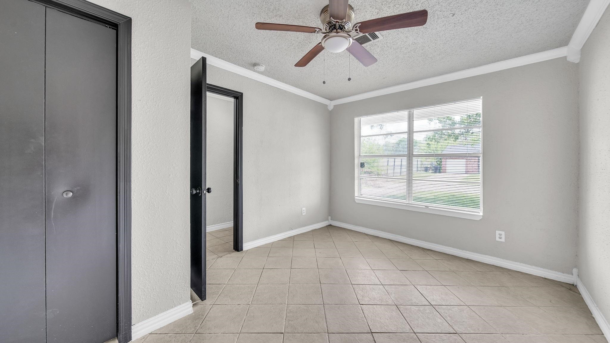 The third bedroom offers a bright, welcoming atmosphere, with two windows overlooking the front yard and inviting an abundance of natural light. Tile flooring, a ceiling fan with integrated lighting, and dual closets provide an appealing combination of comfort, style and generous storage.