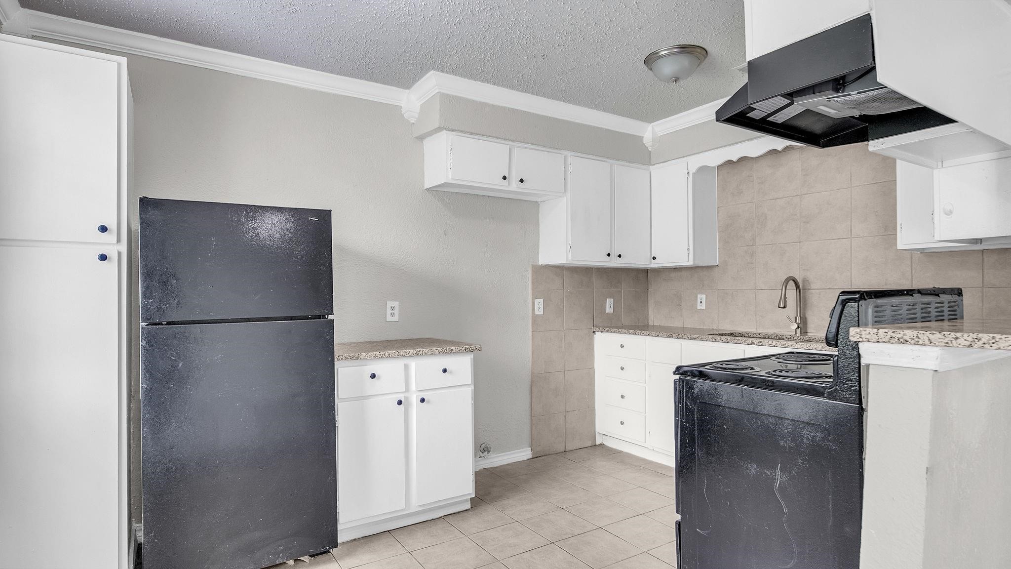 The kitchen combines style and functionality with a four-burner electric range, stainless steel double-basin sink and cabinetry featuring soft-close drawers. A refrigerator, included with the home, completes this beautifully appointed space.
