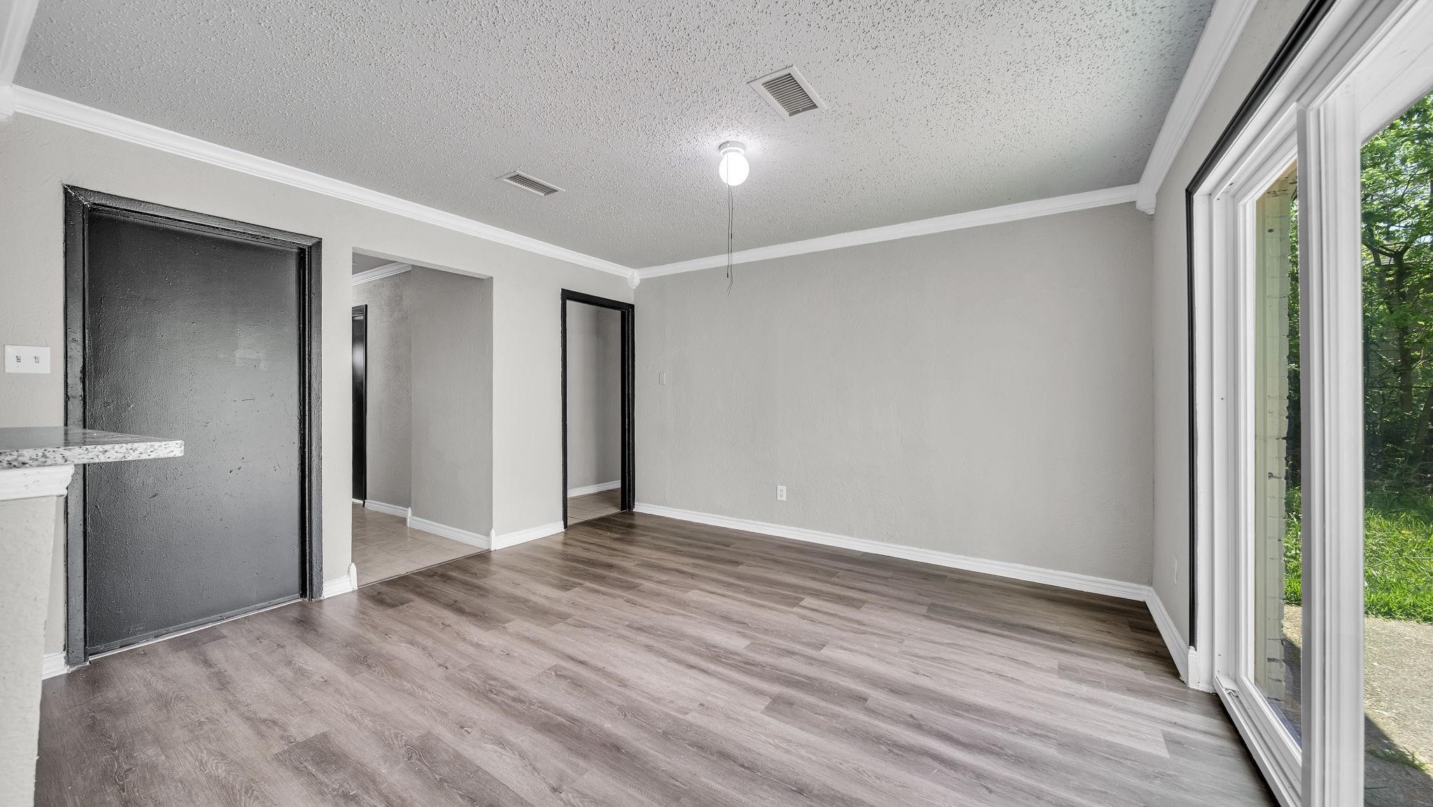 Wide-plank luxury vinyl flooring brings warmth and sophistication to the living room, while elegant crown molding adds a timeless architectural touch. A spacious, inviting setting that beautifully balances comfort with understated luxury.