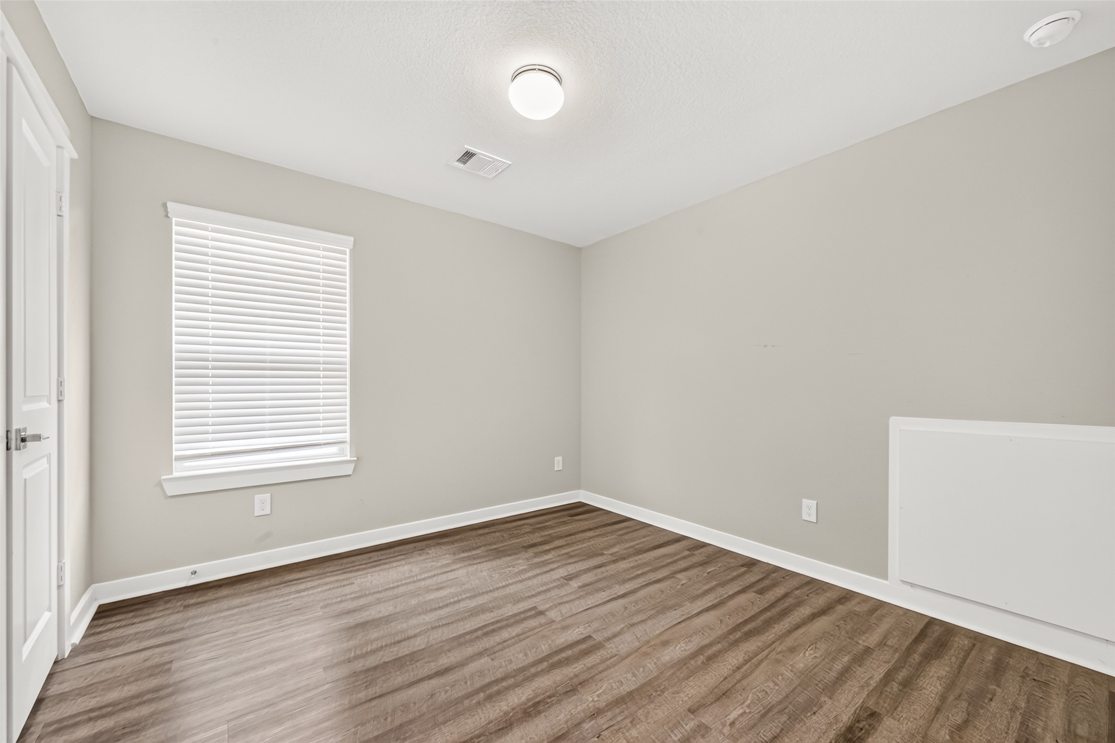 An upstairs secondary bedroom offers natural light, closet storage, and carpet-free flooring.