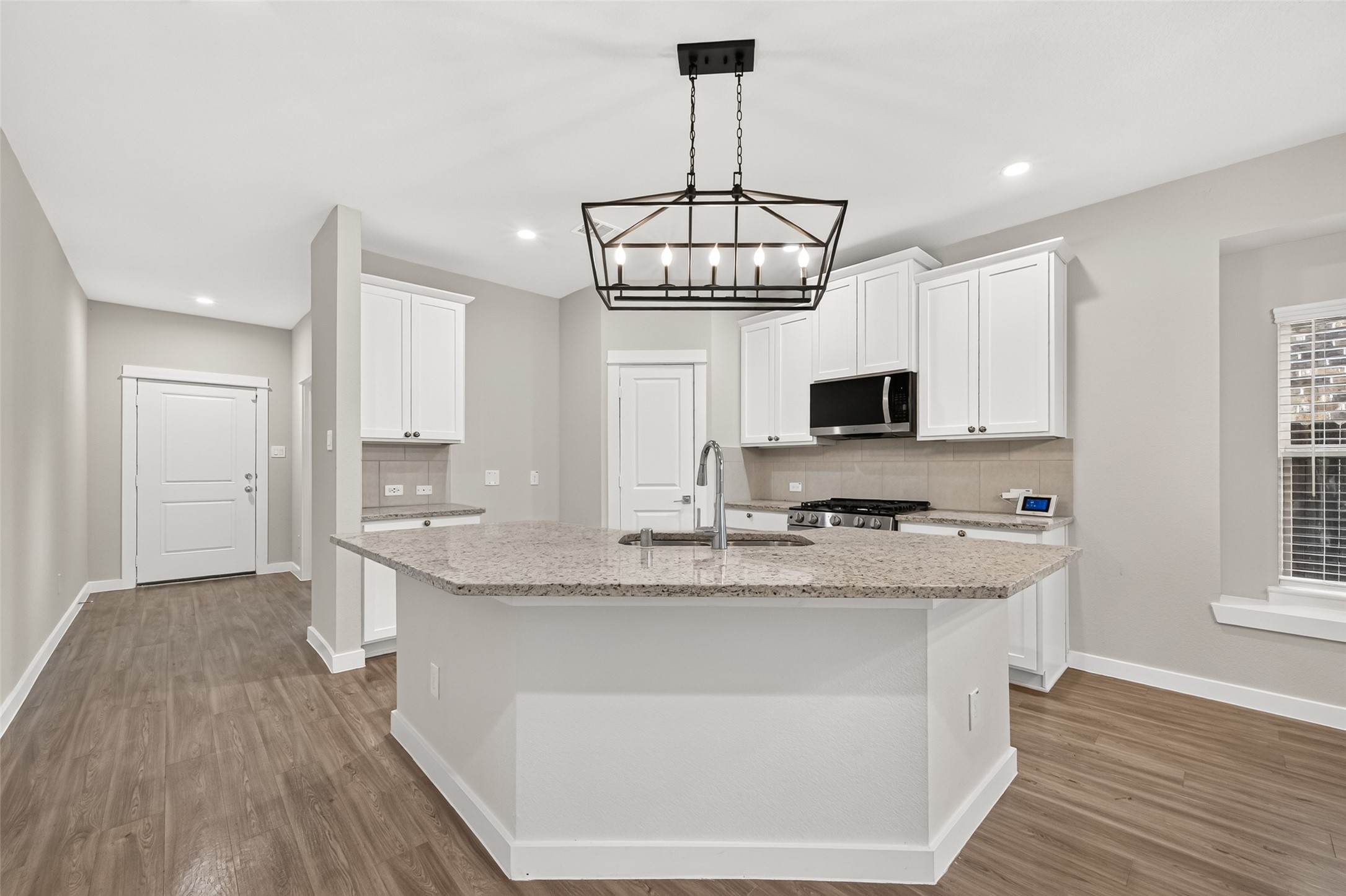 Breakfast-bar seating provides a casual gathering spot, while upgraded lighting adds character above the kitchen counter.