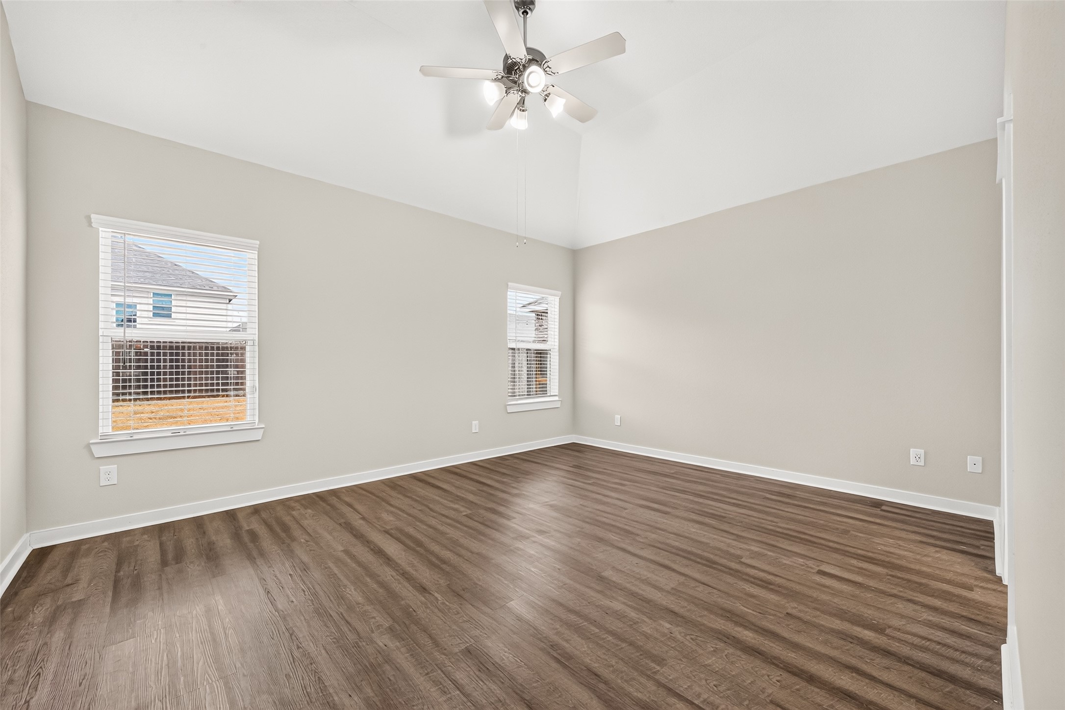 Located downstairs, the primary bedroom offers a comfortable retreat with a ceiling fan and wood-look flooring.