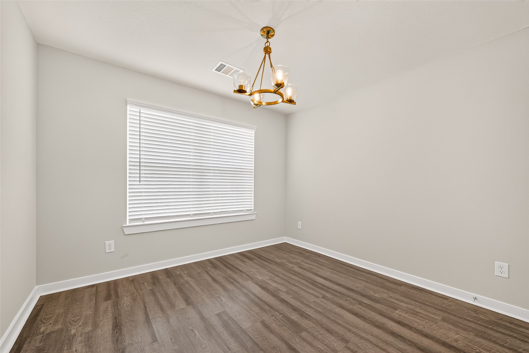 Another secondary bedroom features decorative lighting, neutral walls, and wood-look flooring.