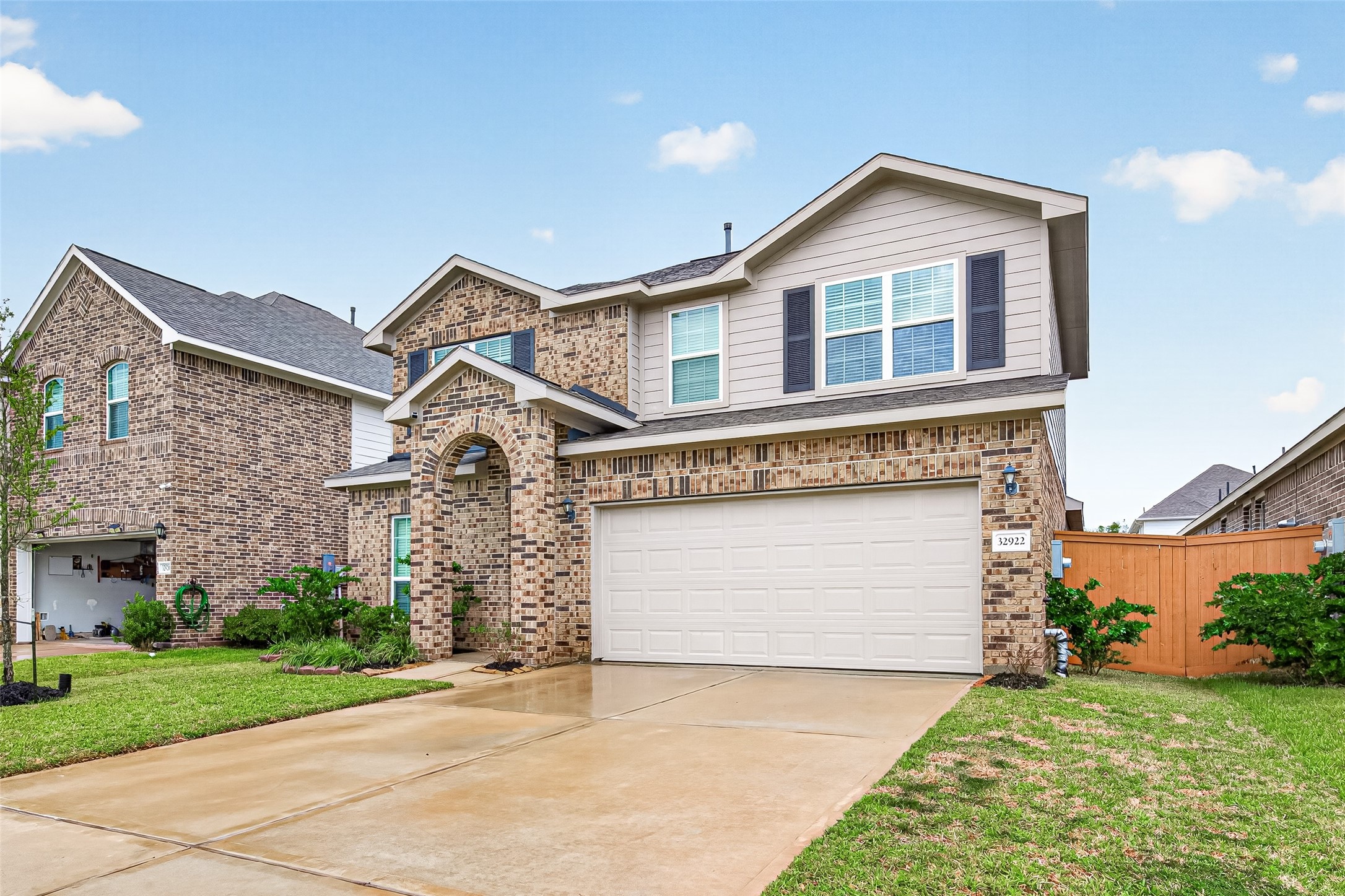 Another view of the brick exterior highlights the covered entry, two-car garage, and front landscaping.