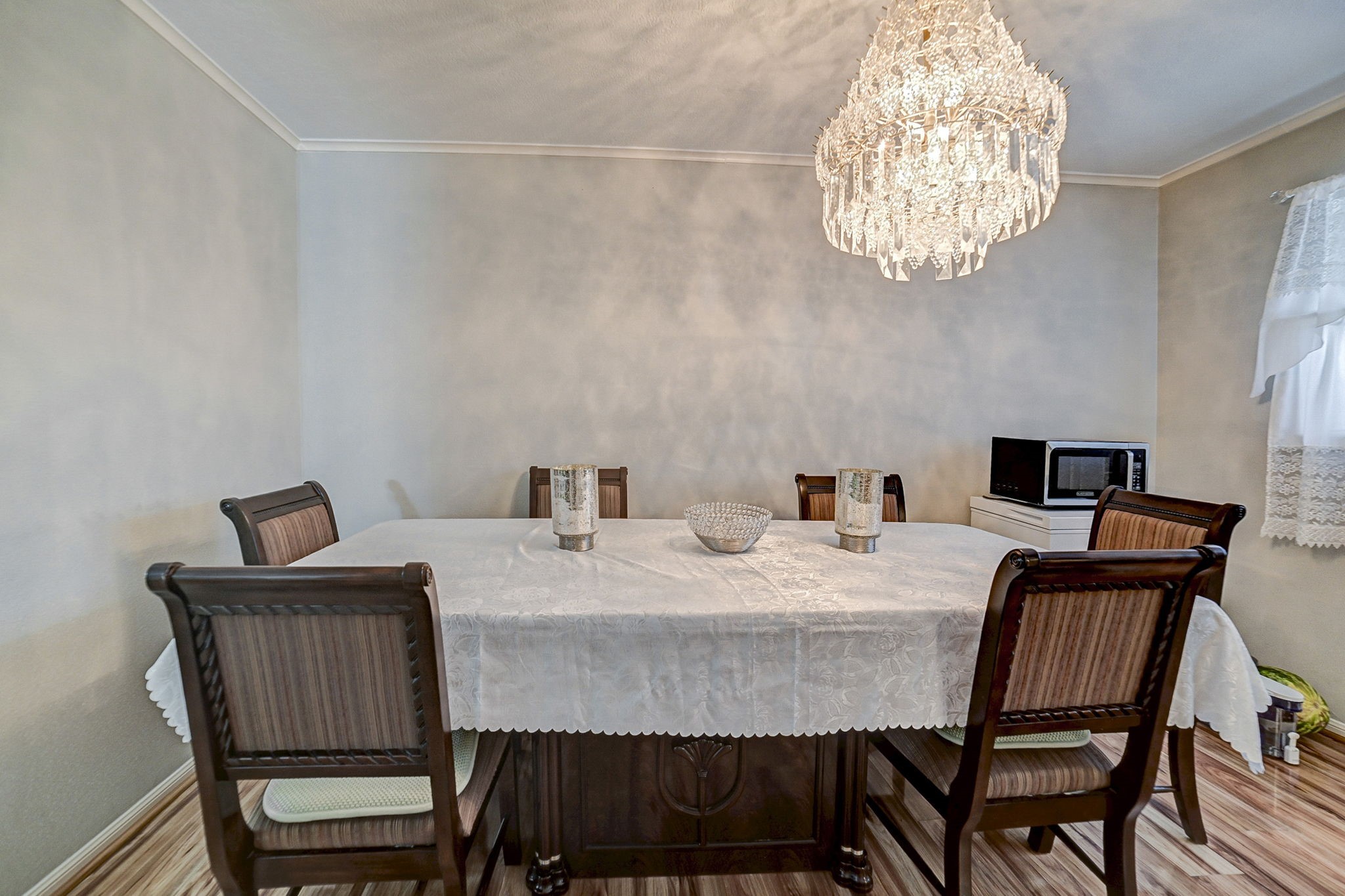 Elegant dining room featuring a sophisticated chandelier, classic table setting with a lace tablecloth, and cozy wooden chairs, perfect for intimate gatherings.