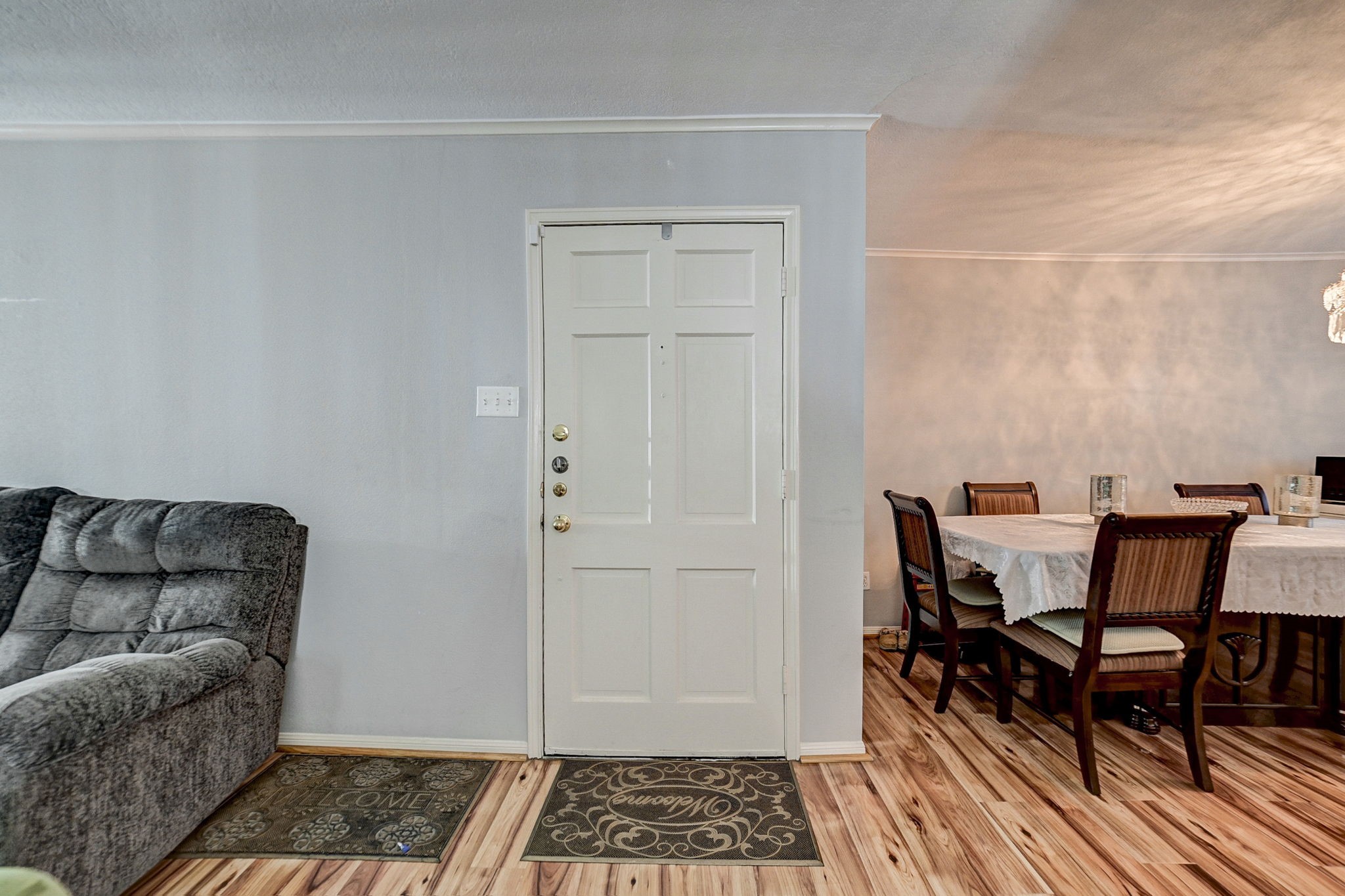Inviting living space featuring a cozy gray sofa and an adjacent dining area with a stylish table setting, enhanced by warm wood flooring and soft lighting.