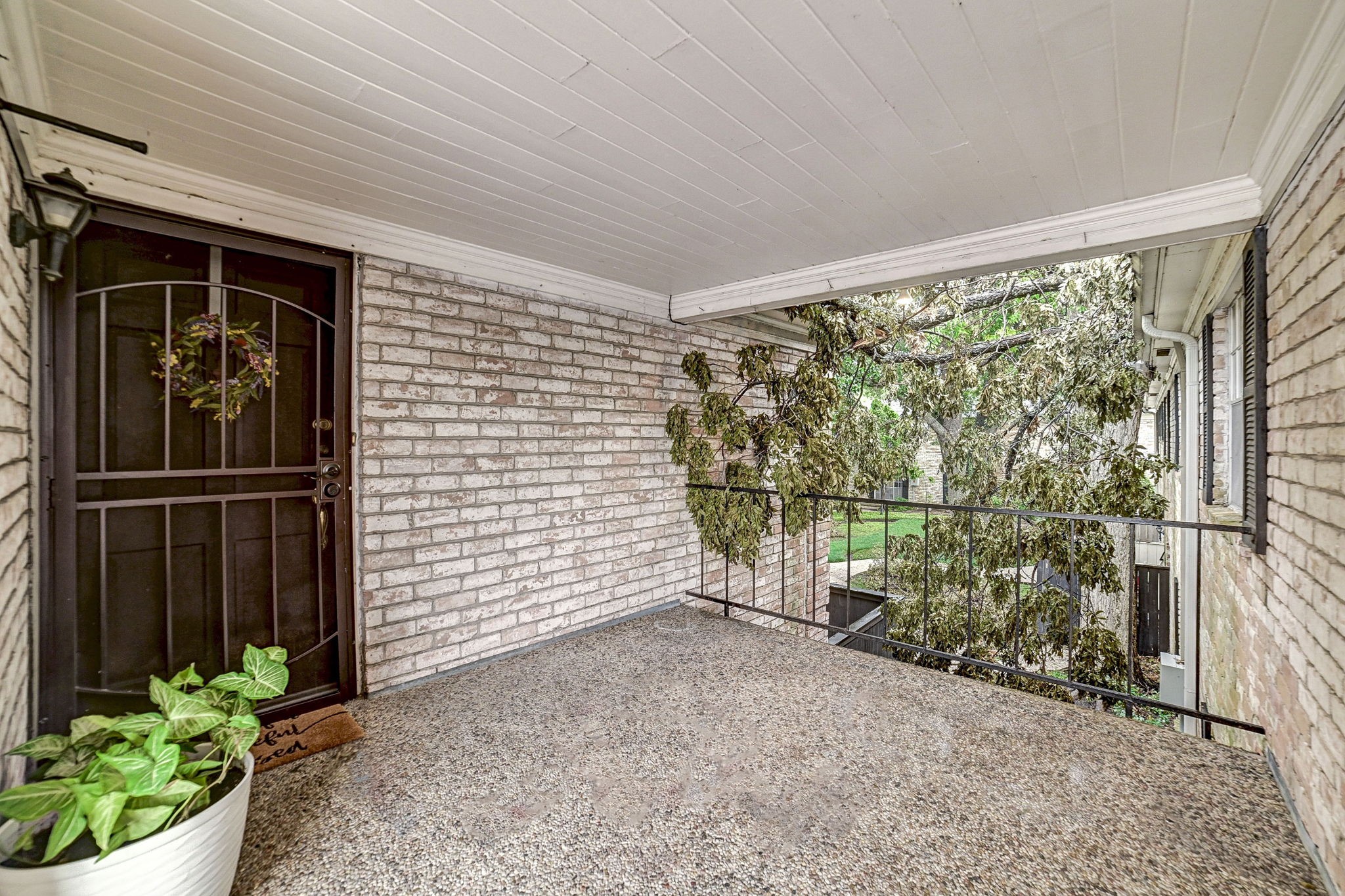 Charming covered porch with a brick facade and wrought iron door, perfect for enjoying the outdoors. Charming covered porch with a brick facade and wrought iron door, perfect for enjoying the outdoors.