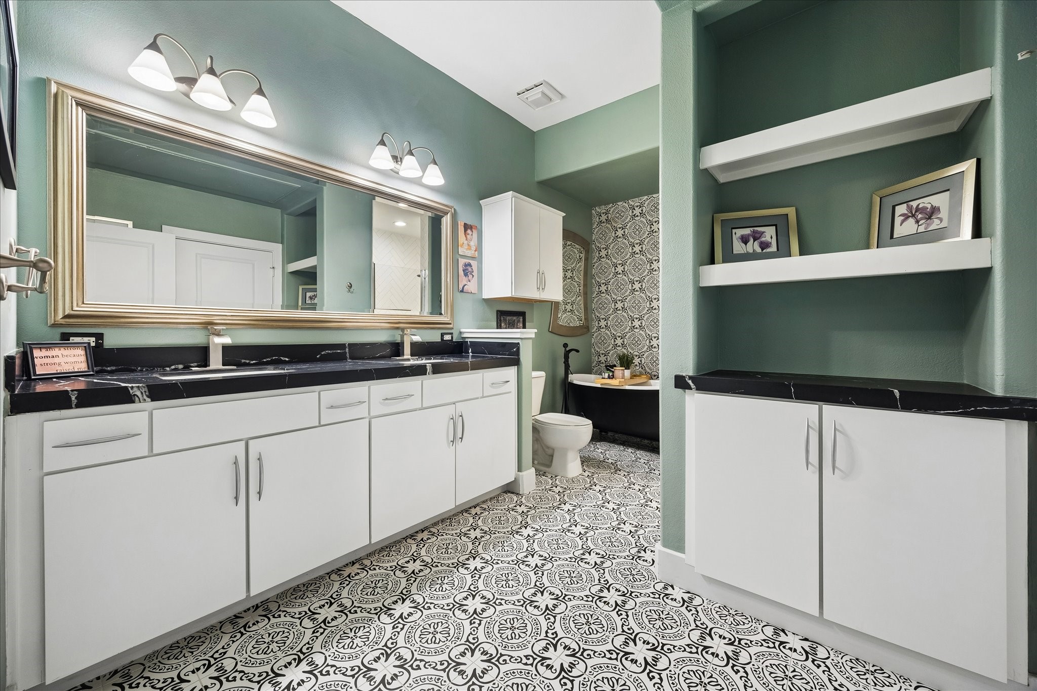 Renovated bath with leathered black quartz, double vanity, designer tile and soaking tub.