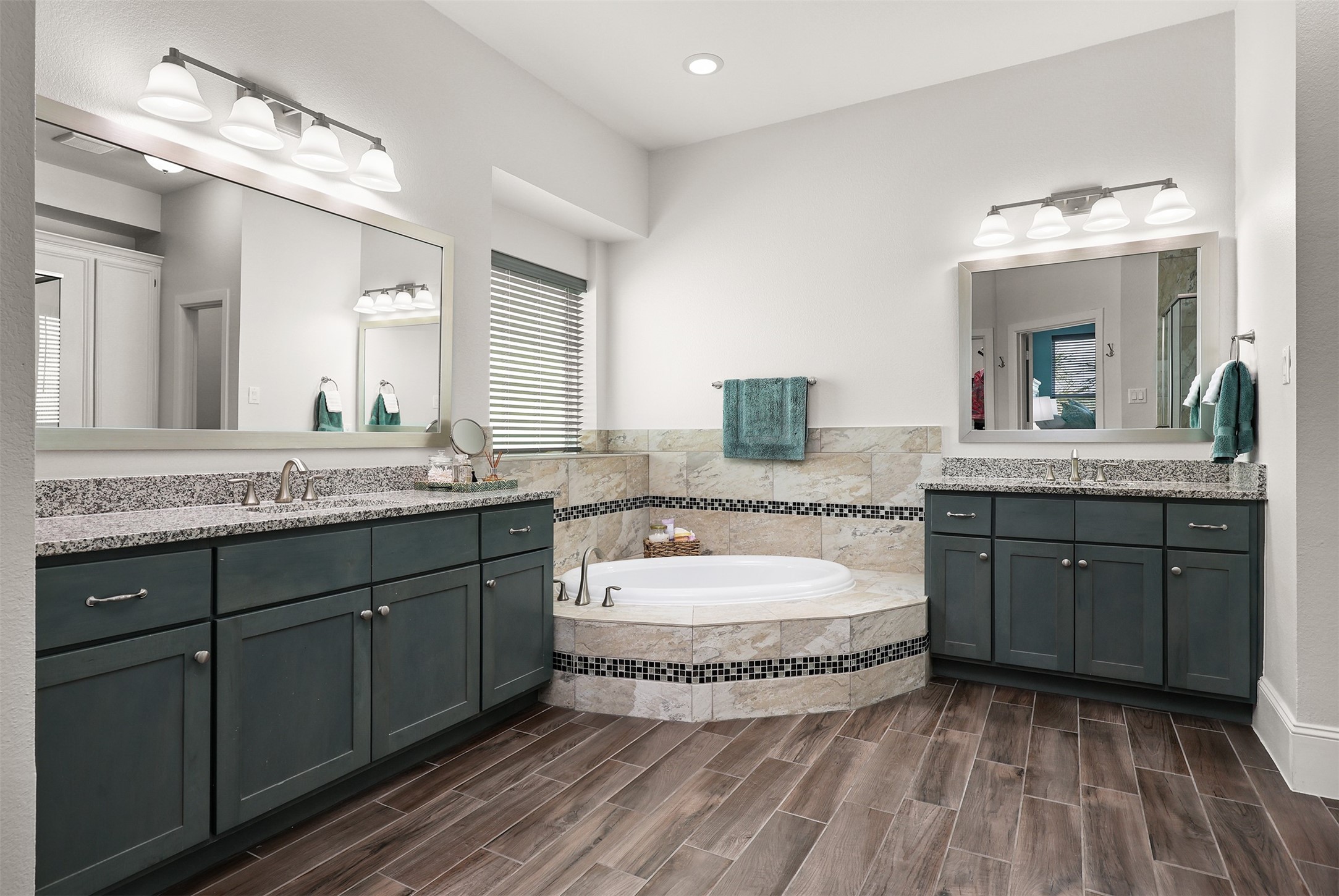 Primary bath with two vanities, granite counters and custom tile work around the soaker tub.
