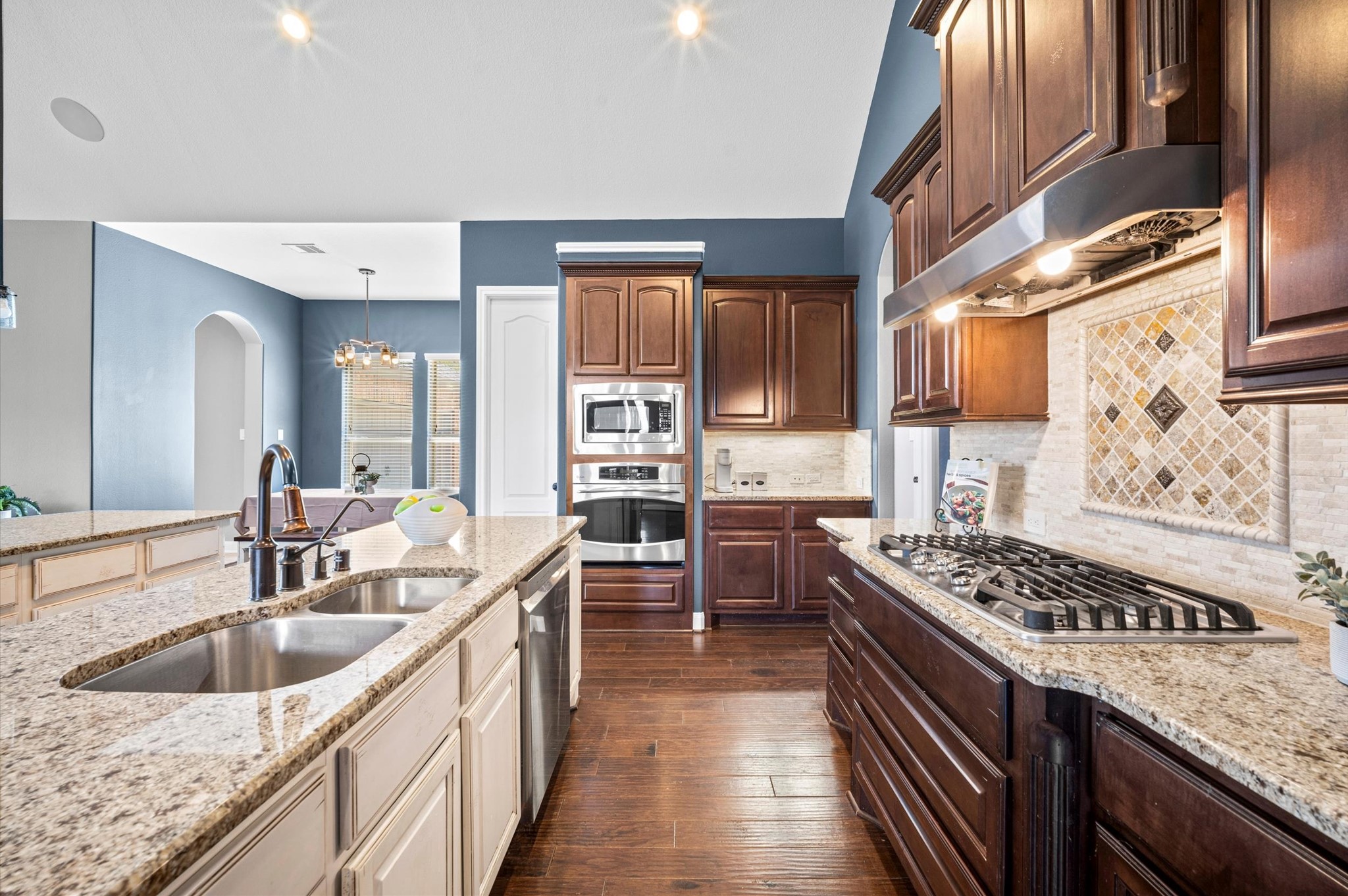 Granite countertops blend beautifully with the rich wood cabinets. Enjoy a double sink and built-in dishwasher on the central island, as well as additional counter space and a breakfast bar on the outer island.