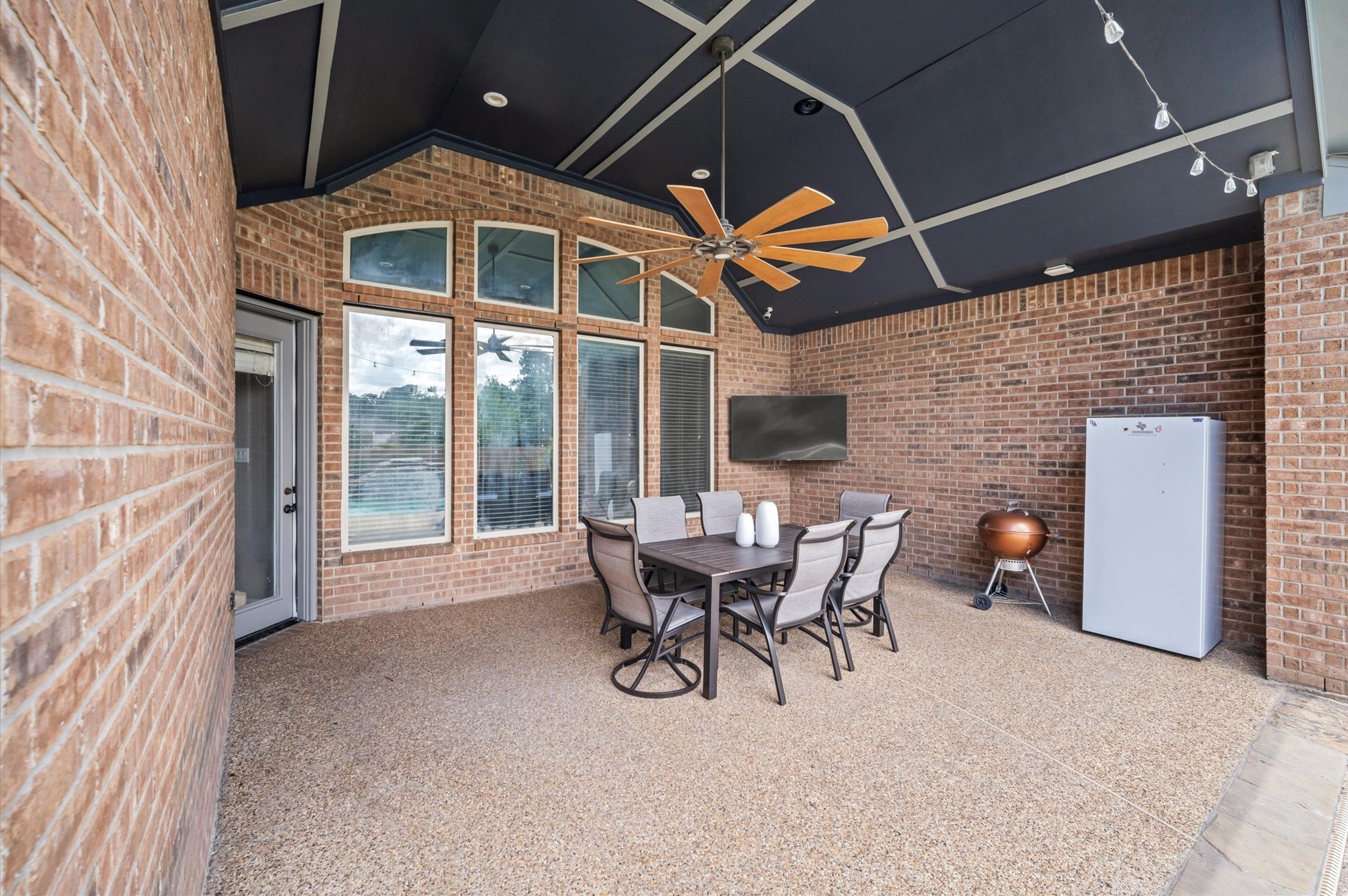 A covered patio, complete with lights and a ceiling fan, is the perfect spot for outdoor chilling and grilling with a poolside view.