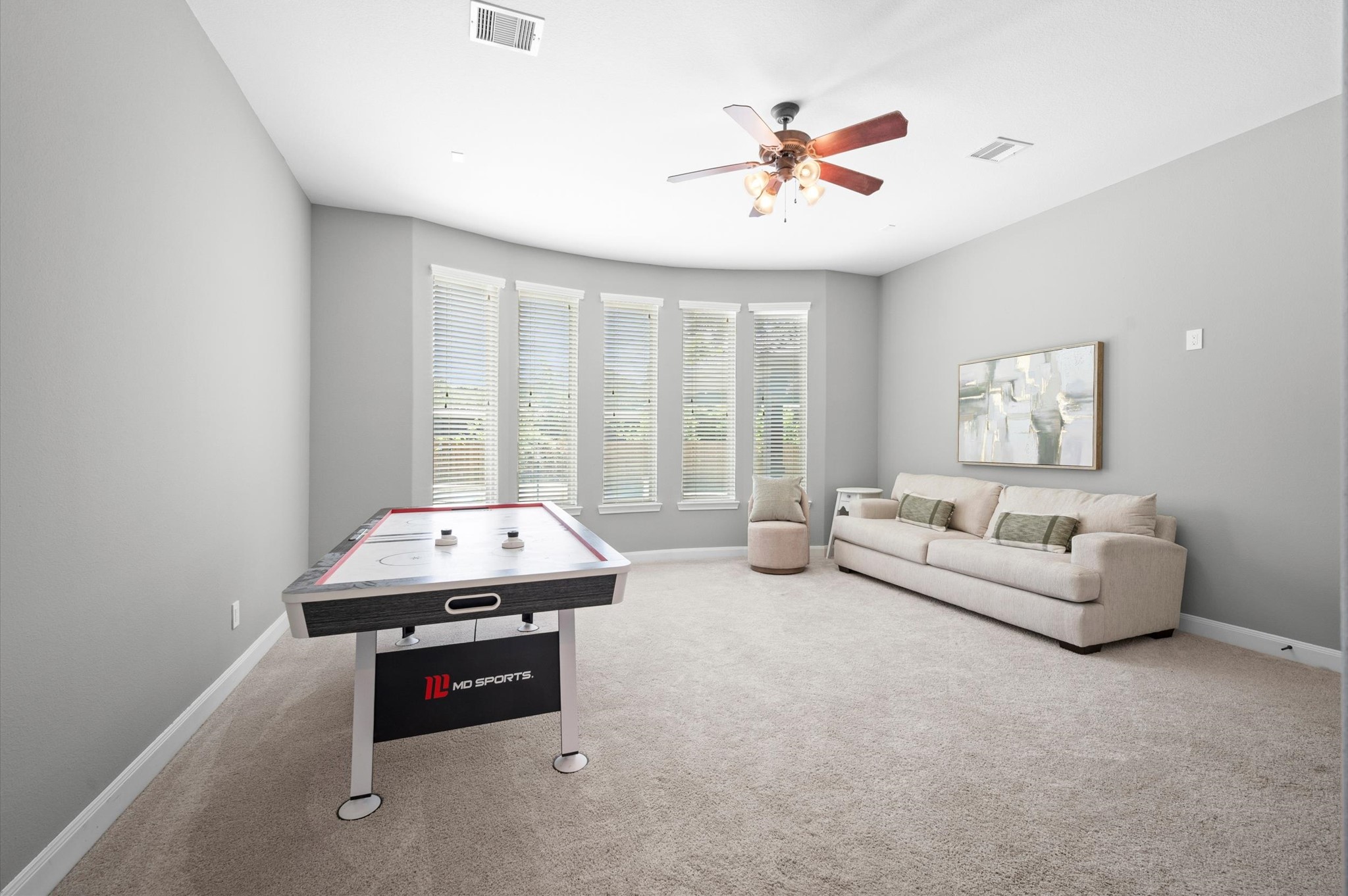 A large flex space serves as a game room or a secondary living space. It is attached to a media room.
