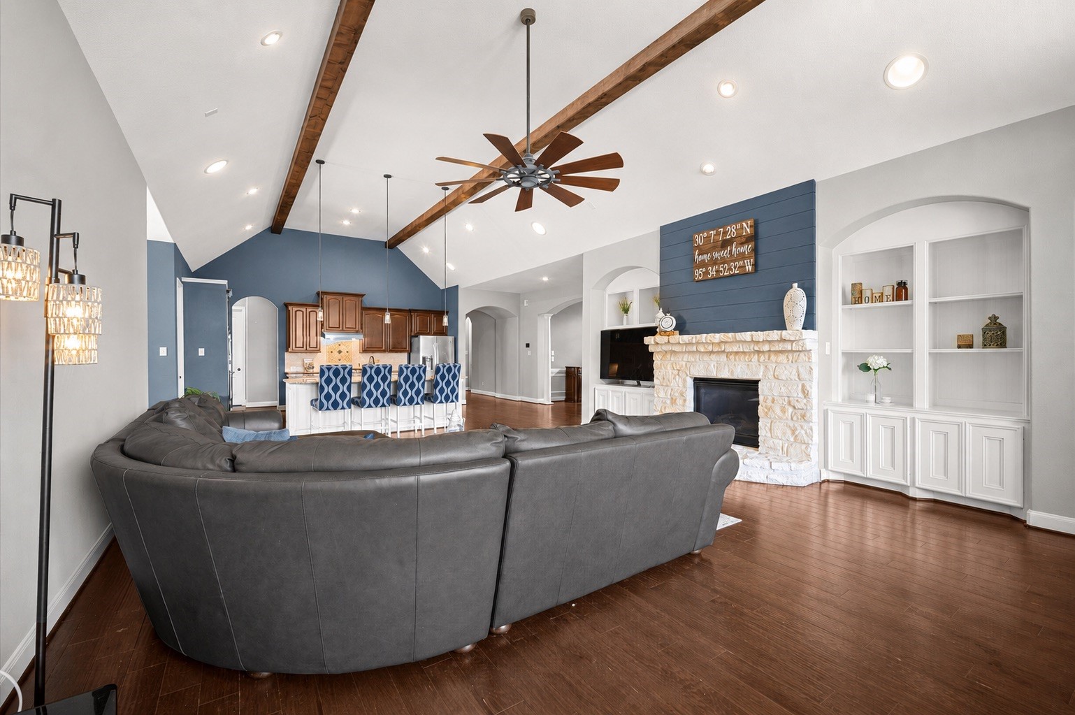 Another view from the living room toward the kitchen. Note the stone accents on the gas fireplace as they complement the exposed beams and wood floors. Built-ins rest on either side for your favorite displays as well as cabinet storage.