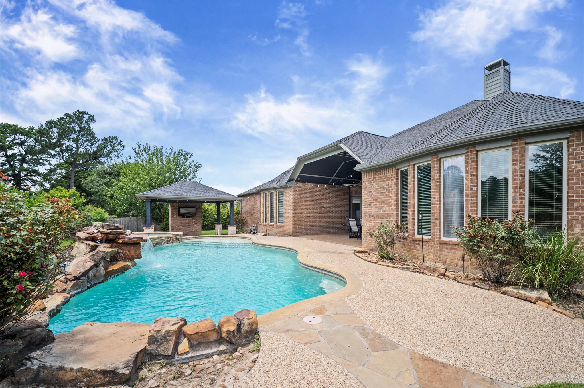 Back to the luxurious backyard splendor! Your new backyard includes a gorgeous pool with a waterfall against a landscaped backdrop. On the far end is a hot tub, near the gazebo. The covered patio has a front row seat to the inviting pool.