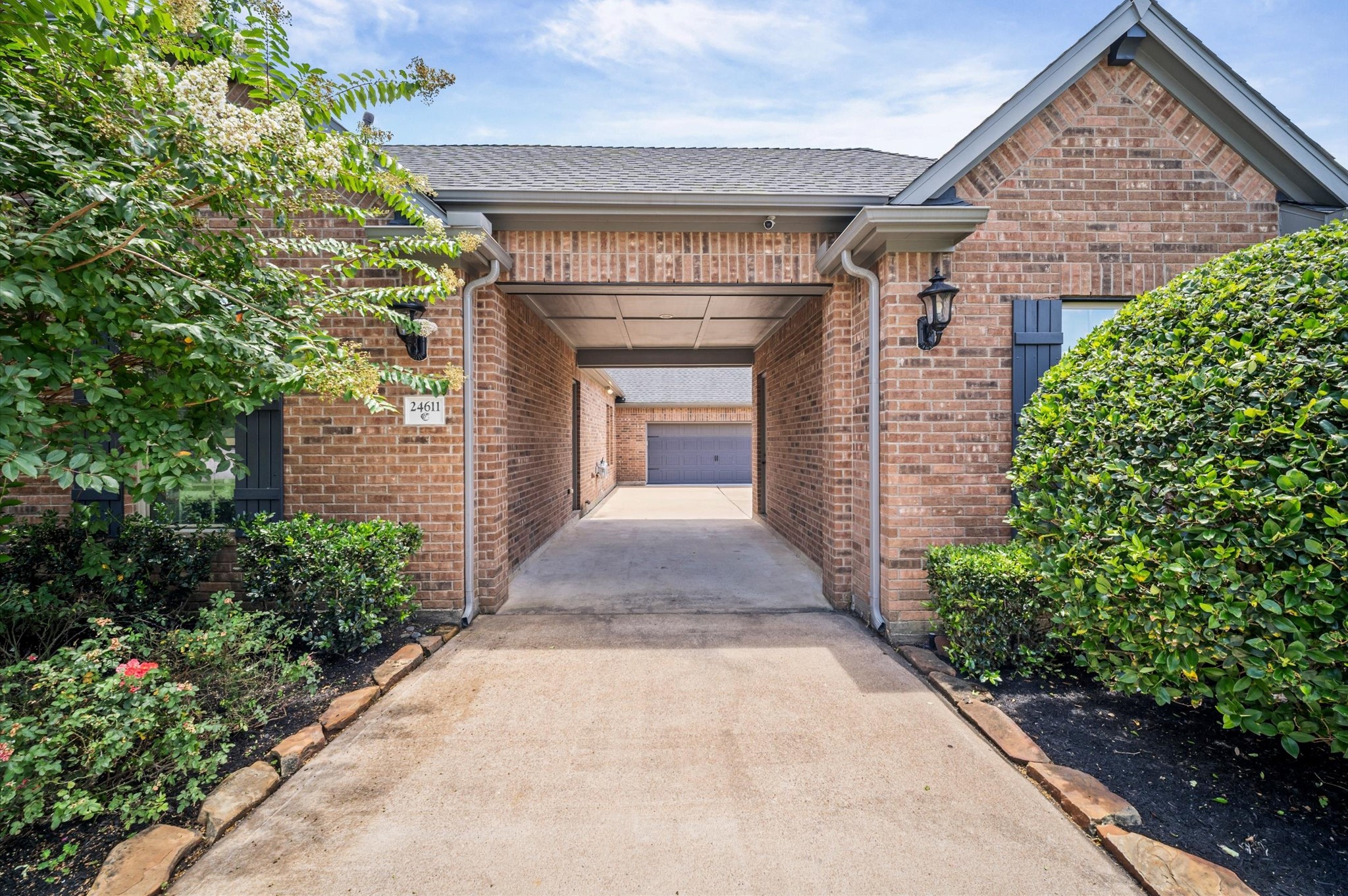 From the front of the home, this is a view of the port-cochre as you head to the garages. Notice the landscaping on either side of the driveway, providing a warm welcome home.