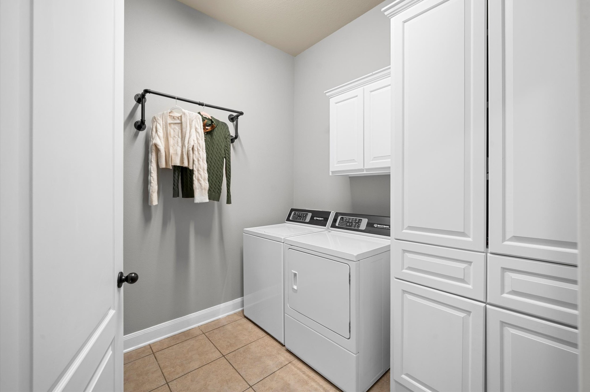 A sizable utility room complete with built-in cabinets and plenty of space for a full-sized washer and dryer.