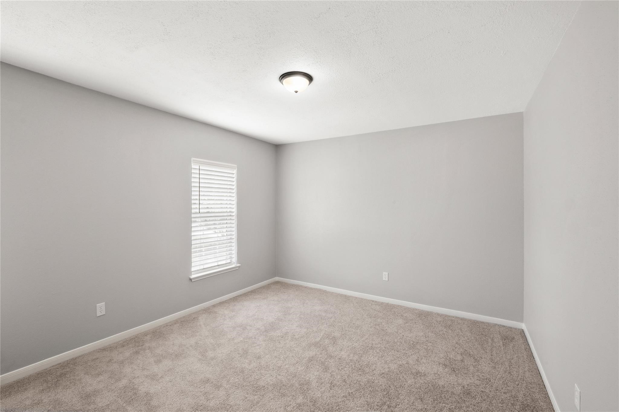 The upstairs second bedroom offers a comfortable retreat with soft carpeting, natural light, and plenty of space for family or guests.