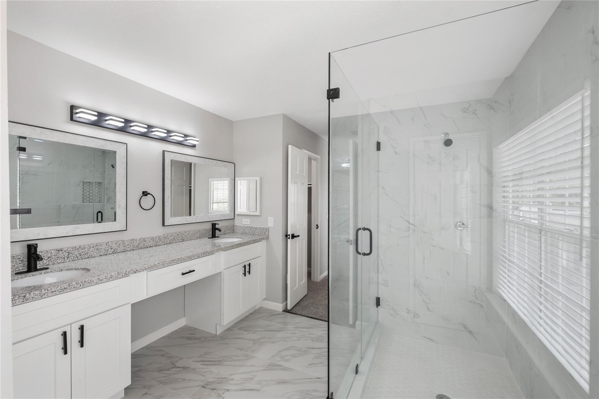 The spa-inspired primary bathroom showcases a frameless glass walk-in shower, dual vanities, and modern finishes throughout.