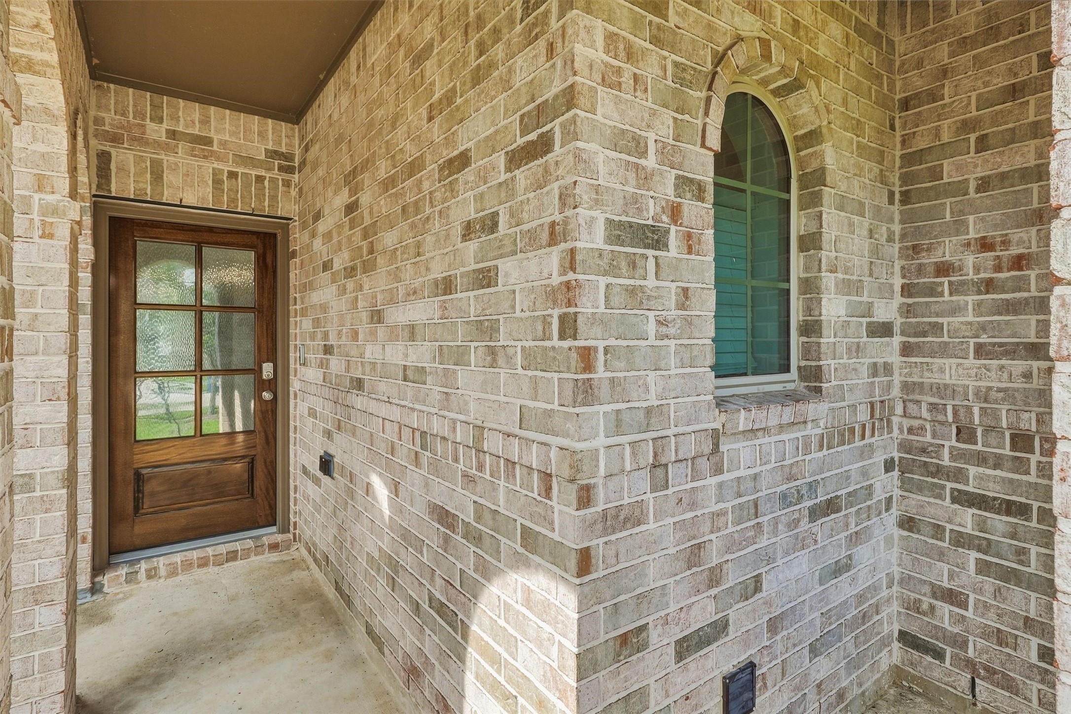 This beautiful front porch has so much style and charm, with brick archways and columns leading to a beautiful wooden door and etched glass. The arched window in the entry, echos the design, and is absolute perfection!