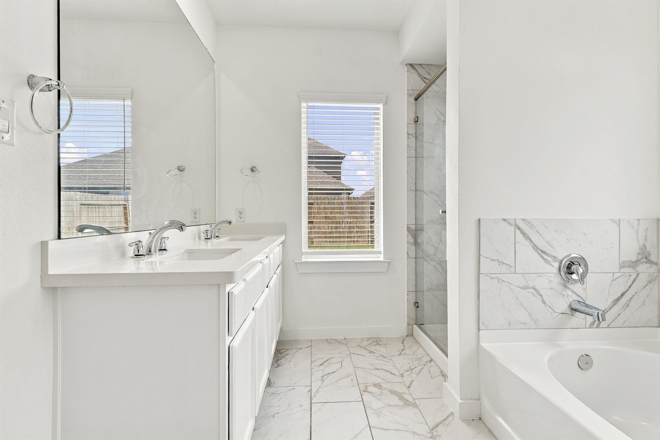 This gorgeous primary bath features double sinks, tile and glass shower, solid surface countertops, undermount sinks, separate soaking tub, and lots of natural light.