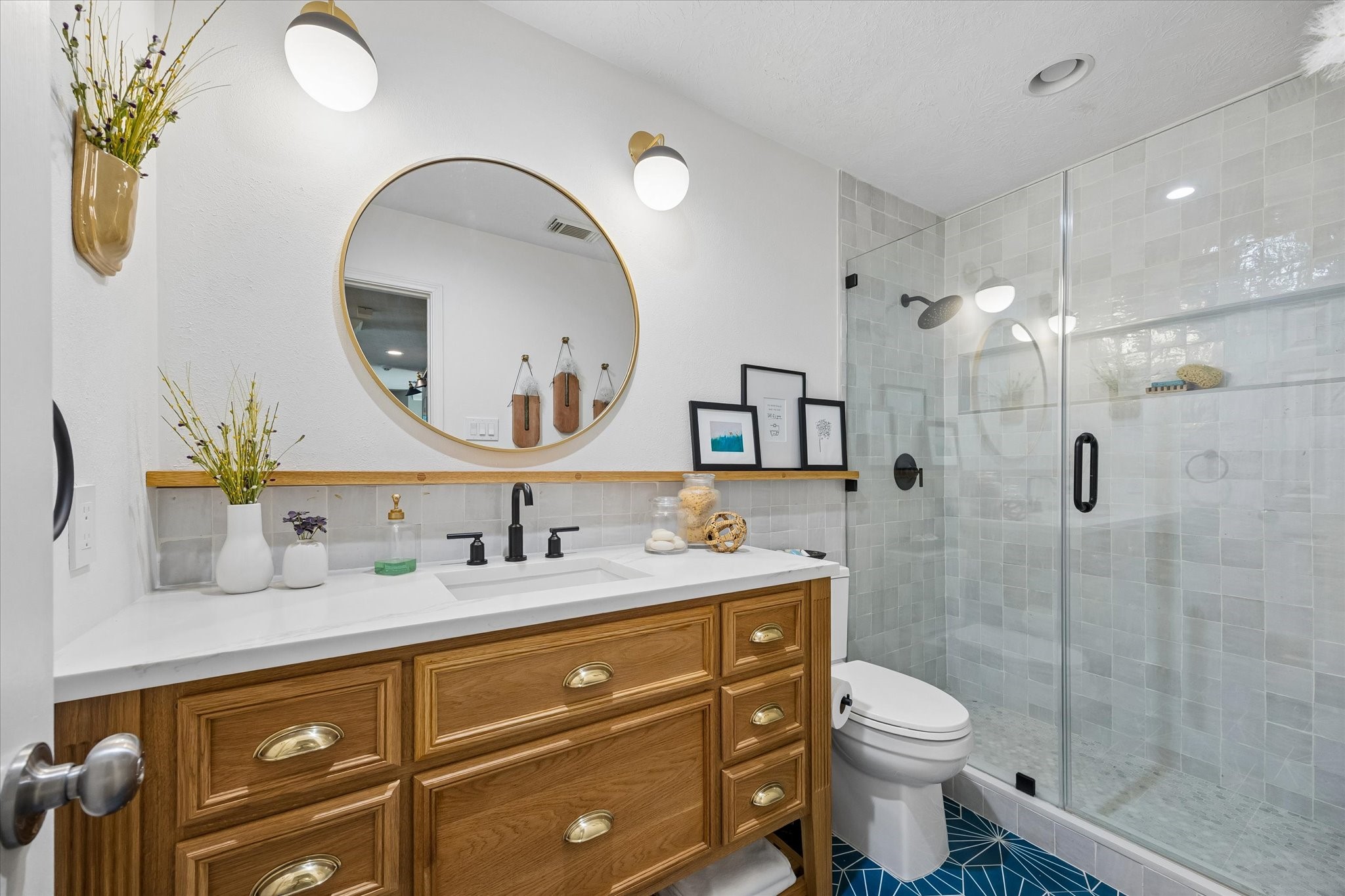 Thoughtfully updated with attractive tilework, a seamless glass shower, and a spacious custom vanity, this bathroom combines everyday convenience with stylish finishes that complement the home's custom details.