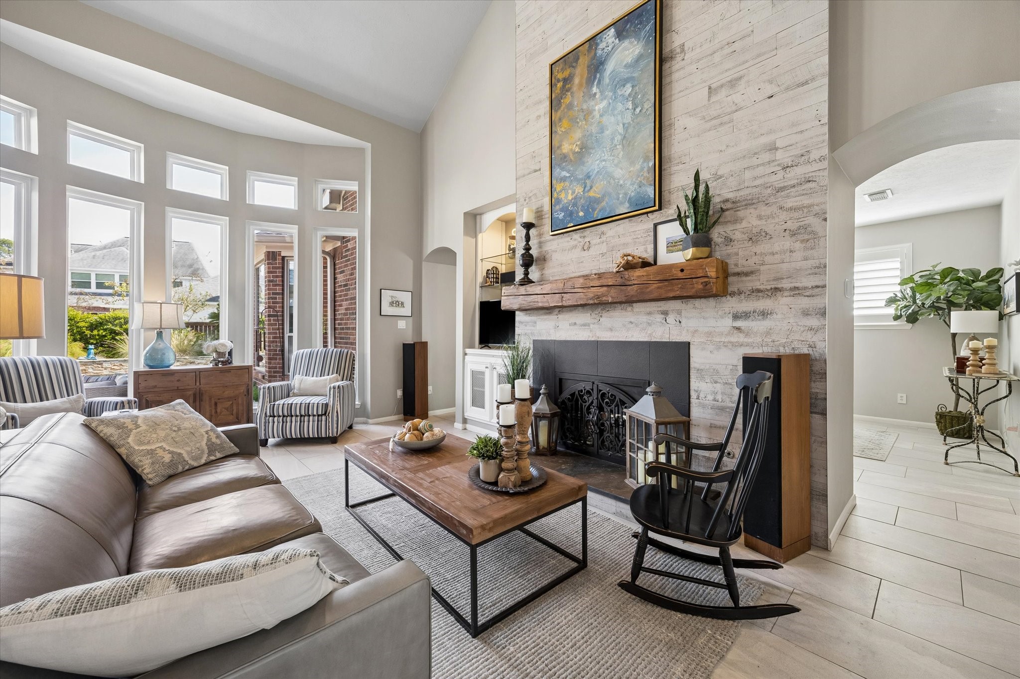 Sunlight streams through the tall windows, bringing the outdoors in and filling this inviting living space with natural light. The striking fireplace serves as a beautiful focal point, while the spacious layout offers plenty of room to relax or entertain.