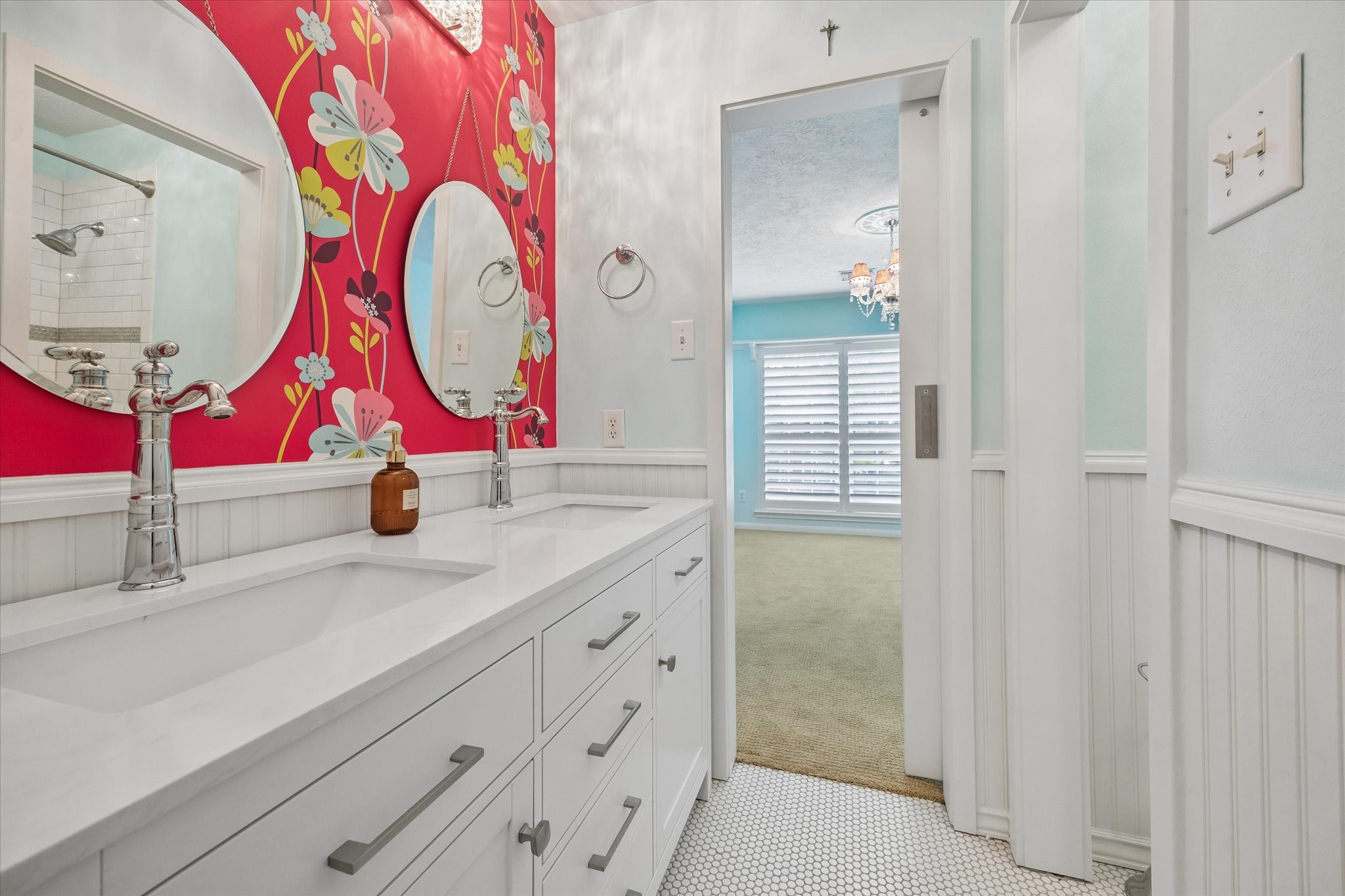 This beautifully updated bathroom combines a spacious dual-sink vanity, fresh white cabinetry, and playful accent wallpaper, creating a bright, inviting space that makes everyday routines feel a little more enjoyable.