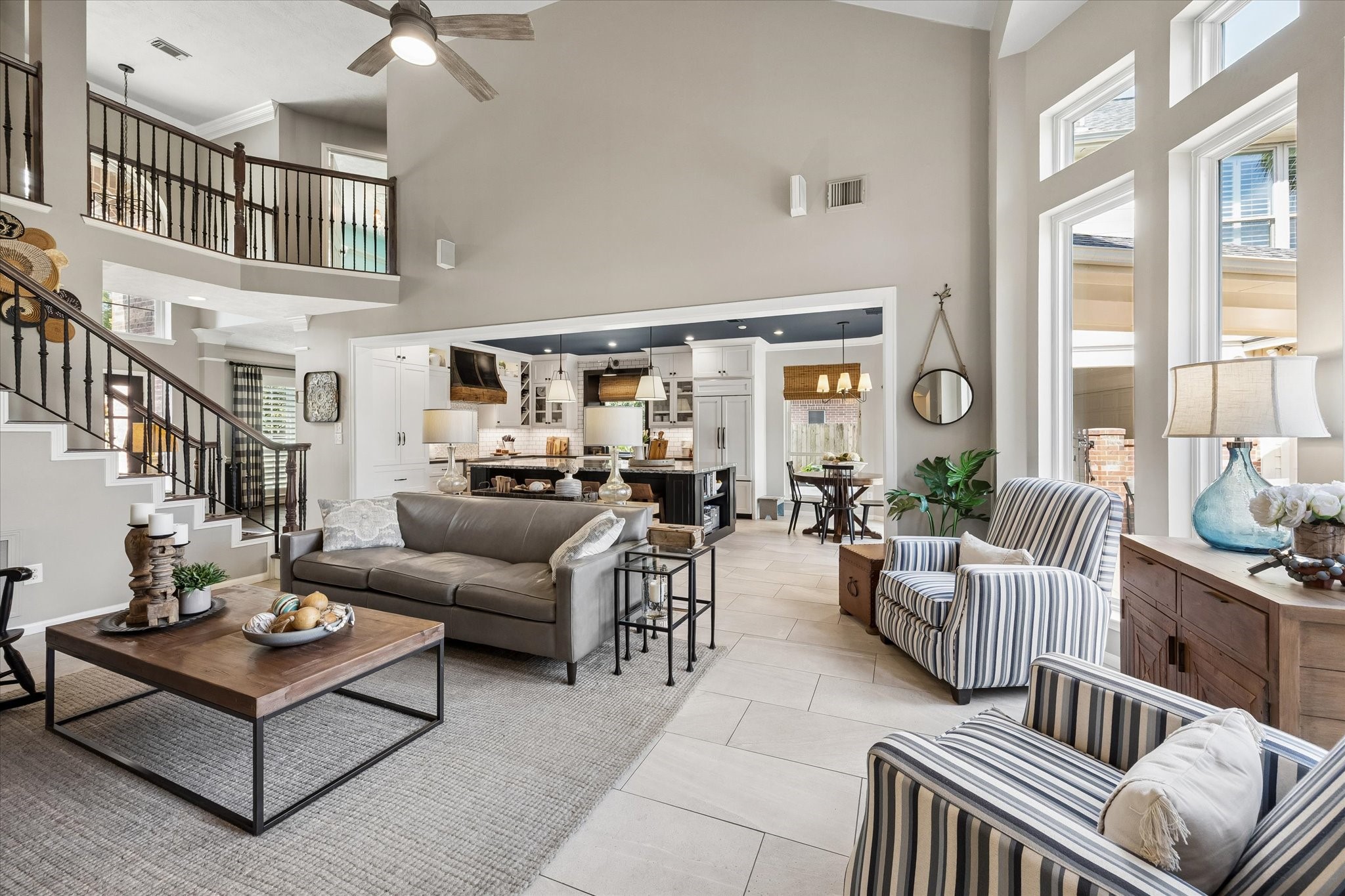 Dramatic ceiling heights, expansive windows, and an open view to the upstairs landing create an airy atmosphere while keeping the living spaces connected.