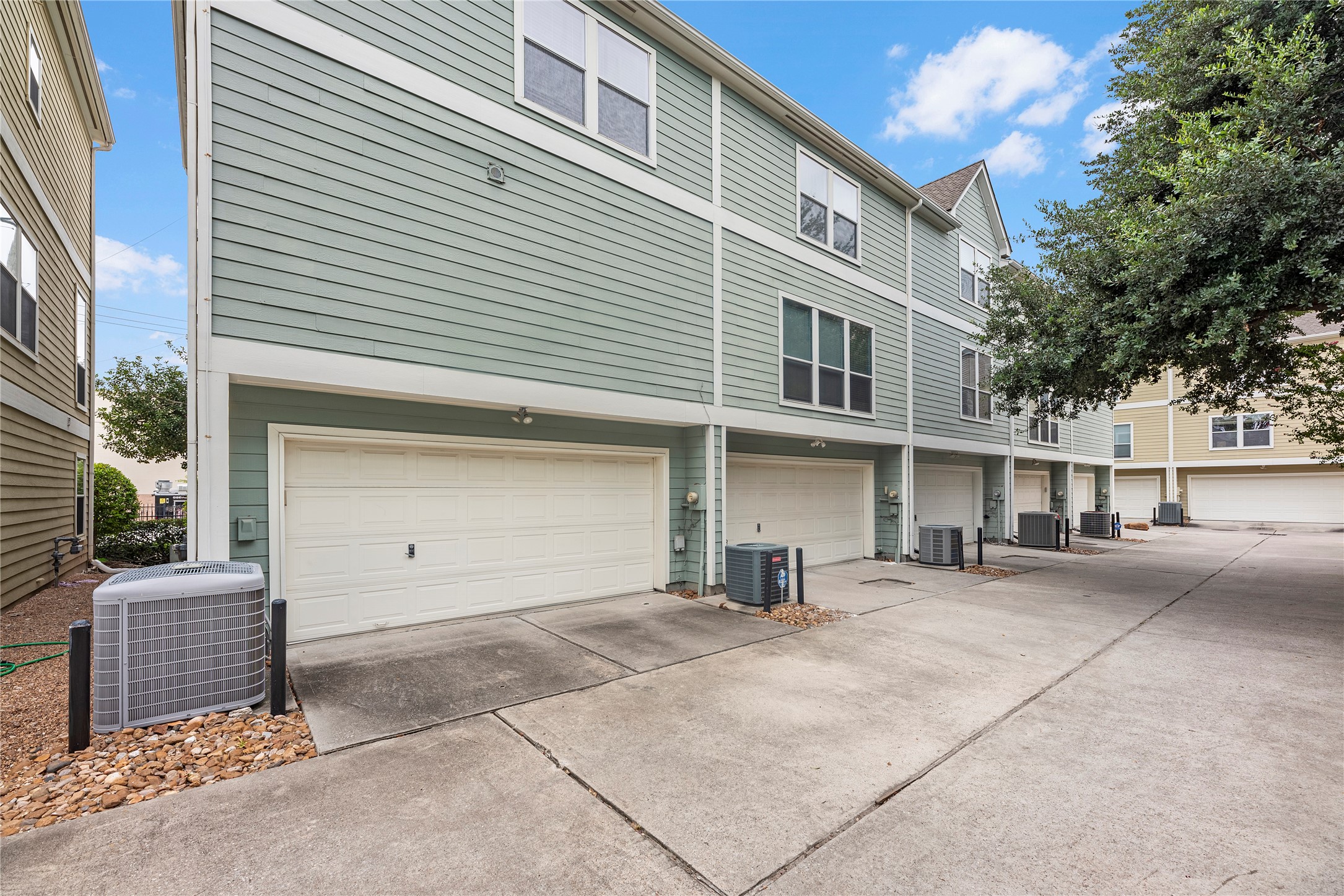 The light exterior color and crisp white trim give this three-story townhome a charming, inviting look. An attached two-car garage and private driveway provide convenient parking, with a dog-friendly green space nearby for four-legged residents to enjoy.