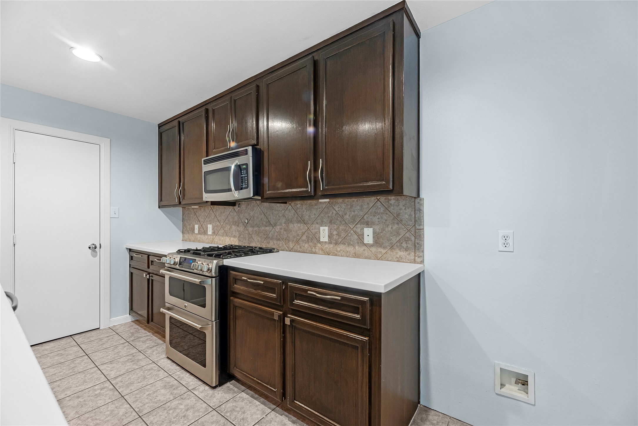 The spacious kitchen features rich brown cabinetry, granite countertops, stainless steel appliances, a gas cooktop, and double ovensperfect for everyday cooking and entertaining.