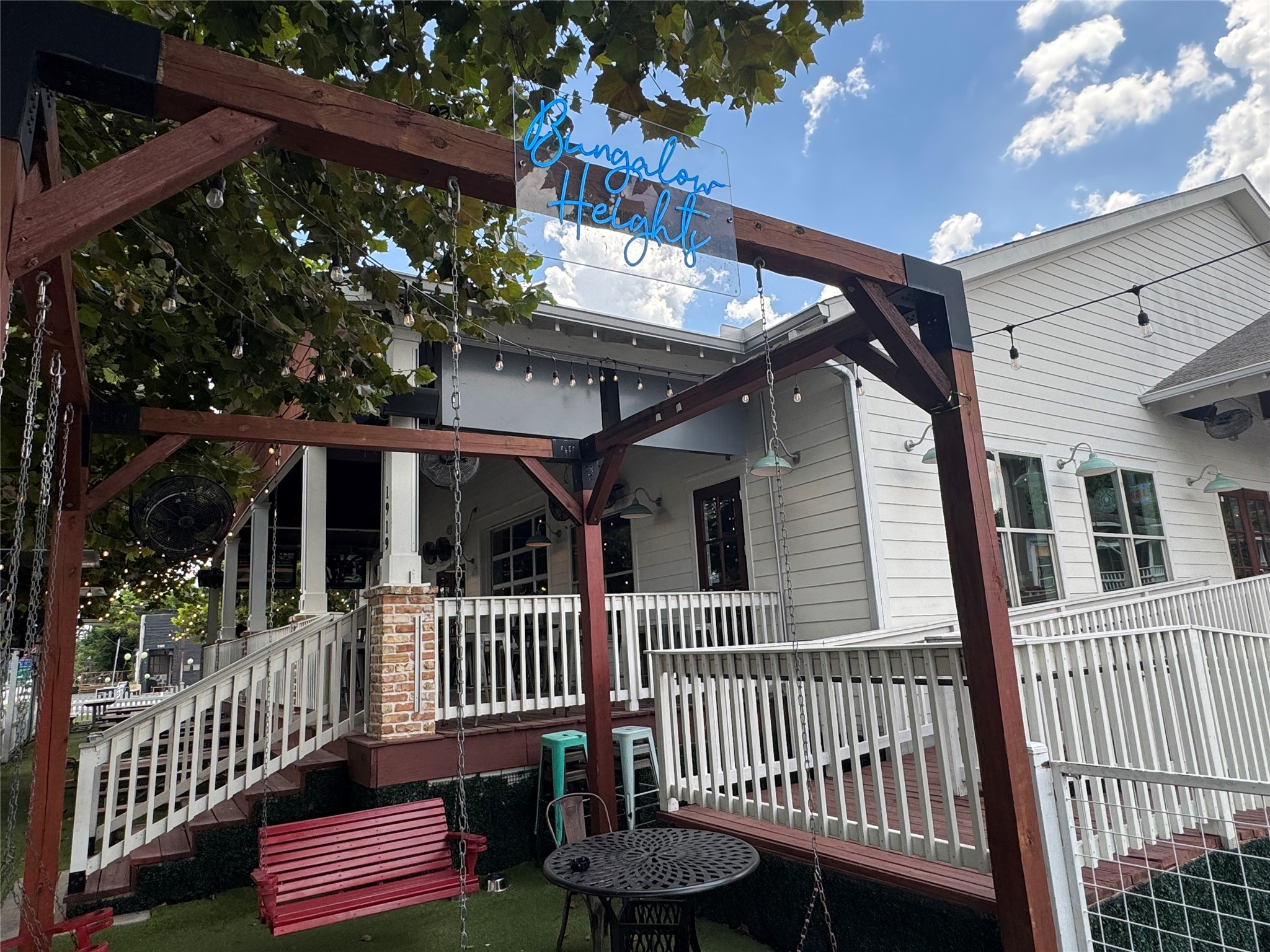 Bungalow Heights features a spacious outdoor seating area with swings and a relaxed atmosphere, providing another nearby spot to gather with friends and enjoy the neighborhood.