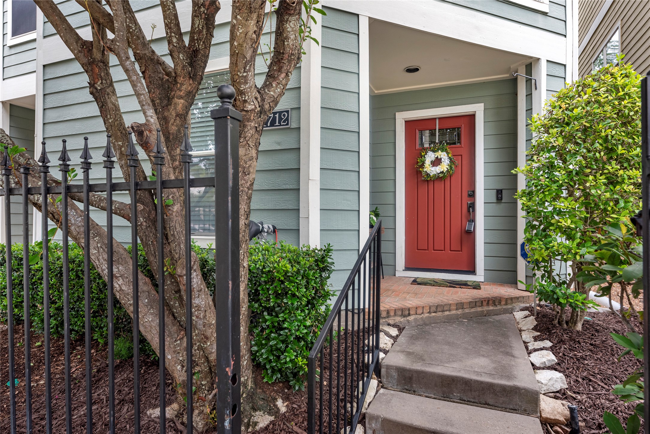 The inviting front entry features brick pavers and fresh plants recently added by the seller for the new owners to enjoy. The seafoam green exterior and covered entry create a welcoming approach to the home, while ongoing front landscaping is included through the HOA for added convenience.