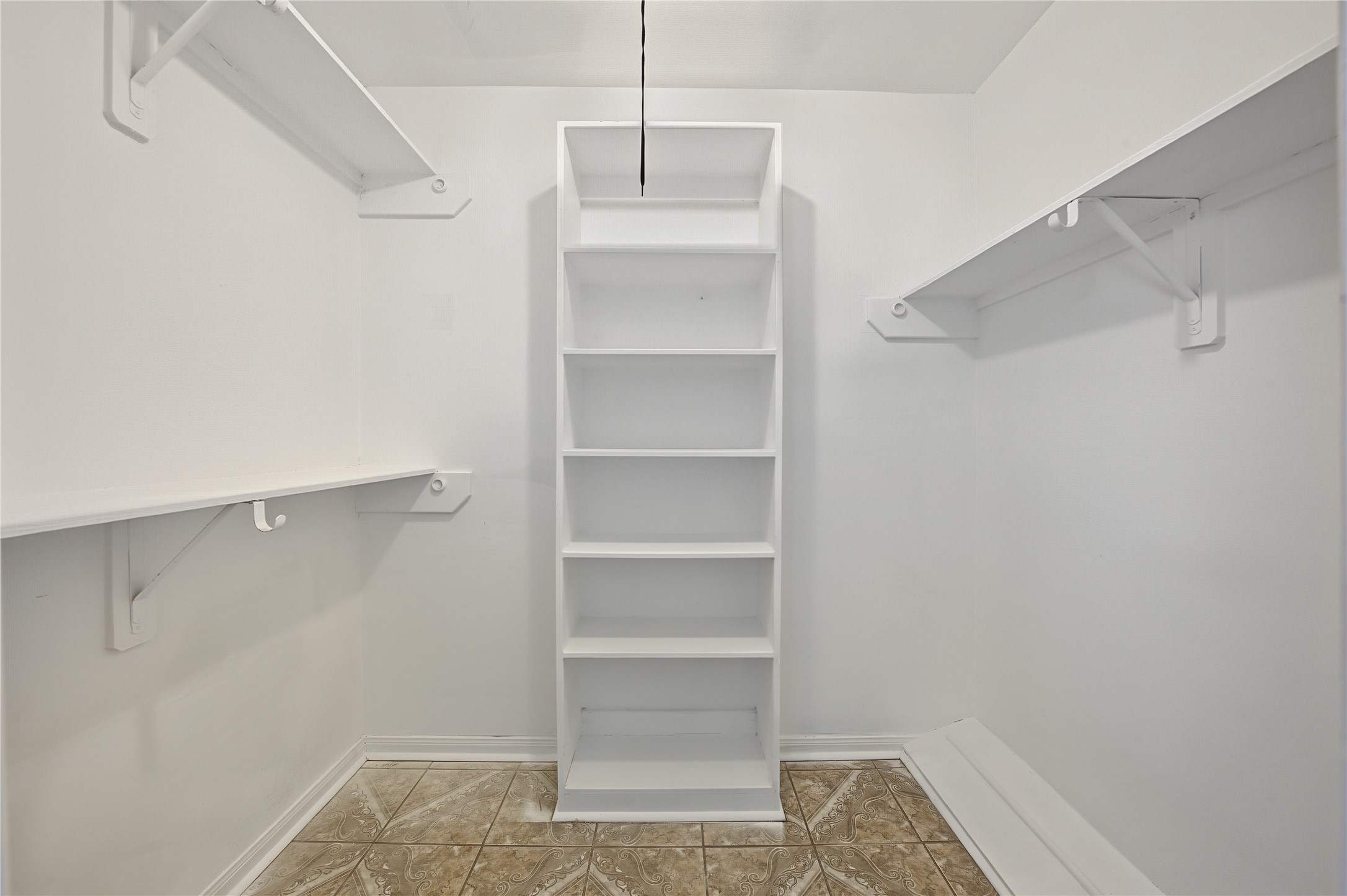 Spacious primary walk-in closet featuring custom built-in shelving and fresh interior paint.