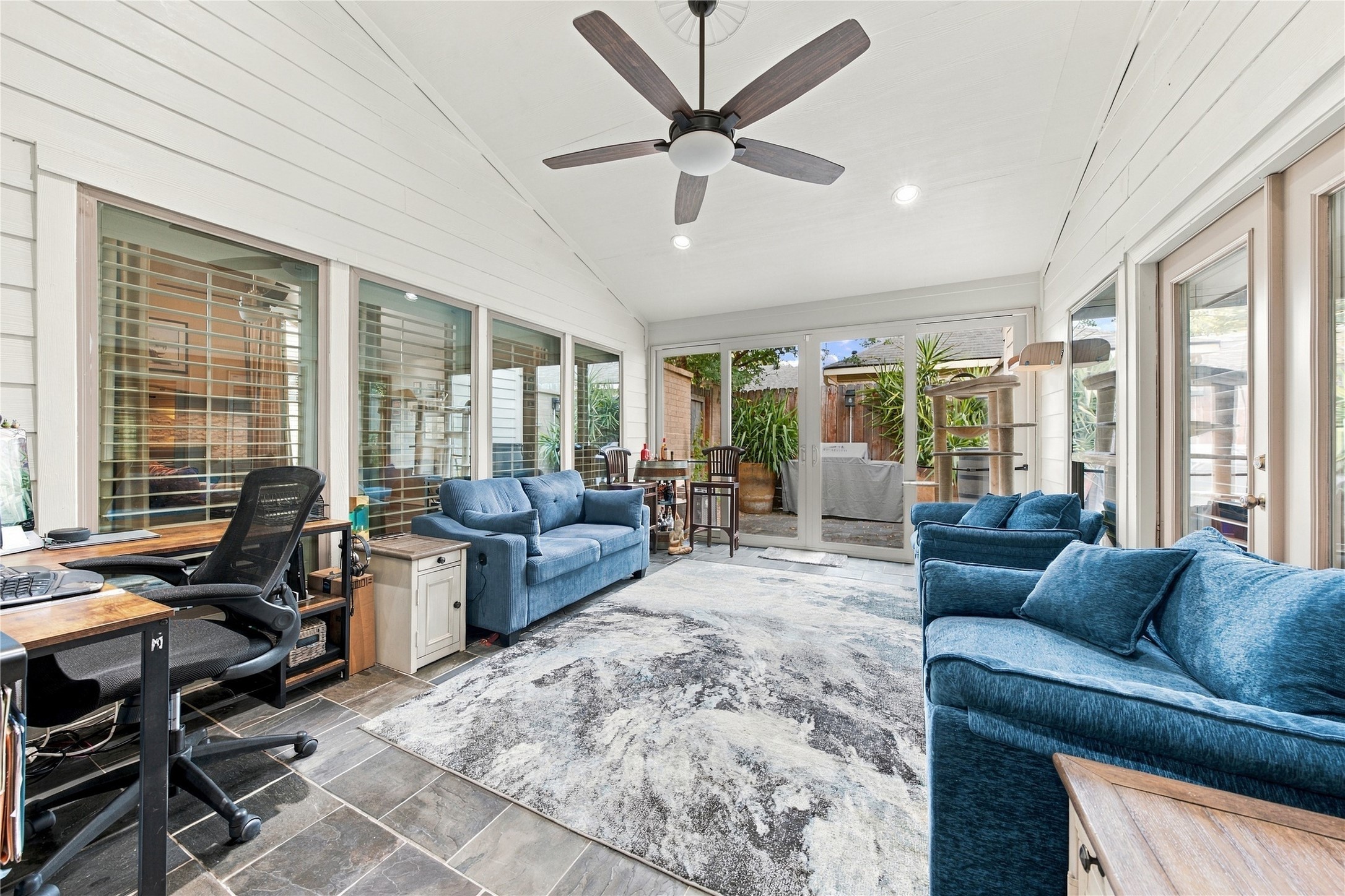The sunroom is a true standout! A vaulted white-planked ceiling, slate tile floors & a wall of sliding glass open straight to the patio, while shuttered windows & French doors connect it to the rest of the home.