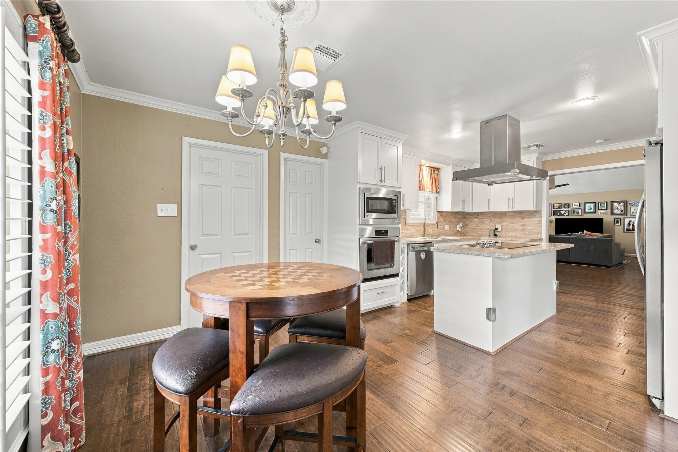 Charming breakfast nook with chandelier, crown molding & white French doors opening to a private side patio while the opening adjacent the French doors leads into to the formal dining room.