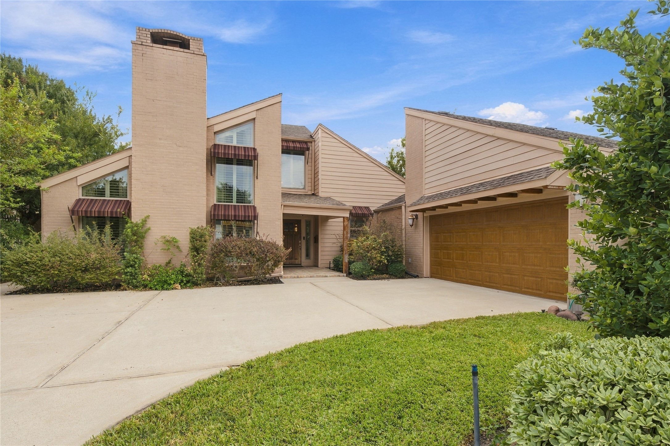 Curved double-wide driveway leads to the attached two-car garage, offering plenty of extra parking for residents & guests. Exposed rafter tails under the eave add a charming architectural detail.
