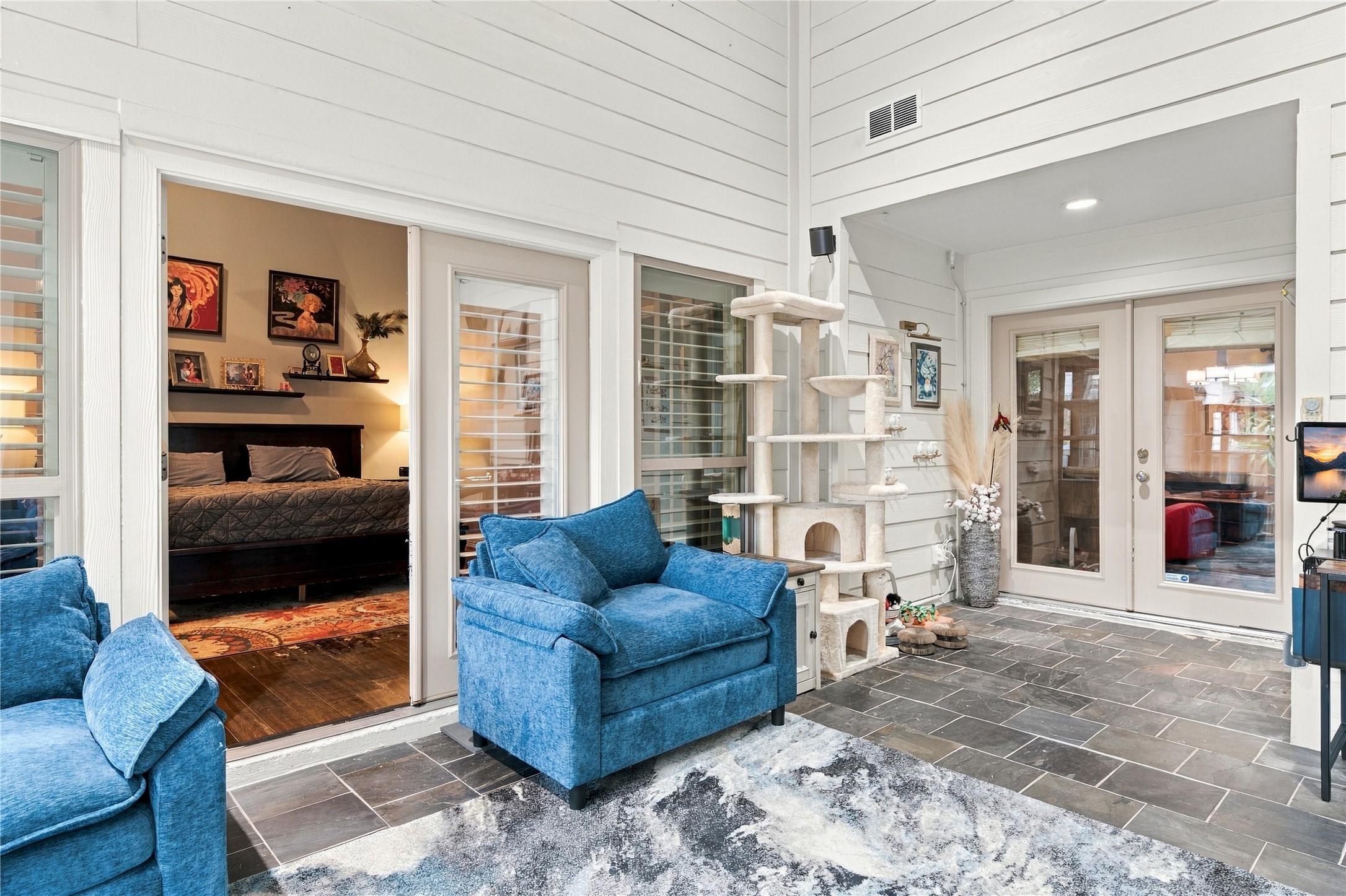 French doors open from the sunroom into the primary suite, placing the sunroom at the center of the home between the living spaces & the private wing.