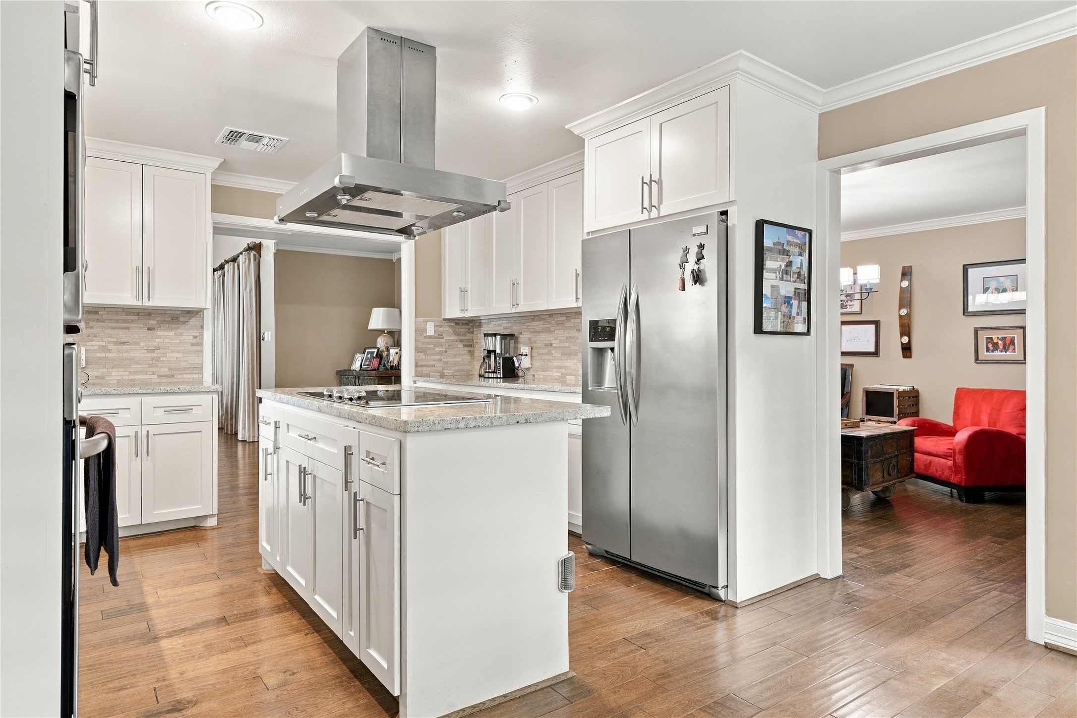 Stainless steel side-by-side refrigerator is framed by shaker style cabinetry with storage above, and the island adds additional storage.