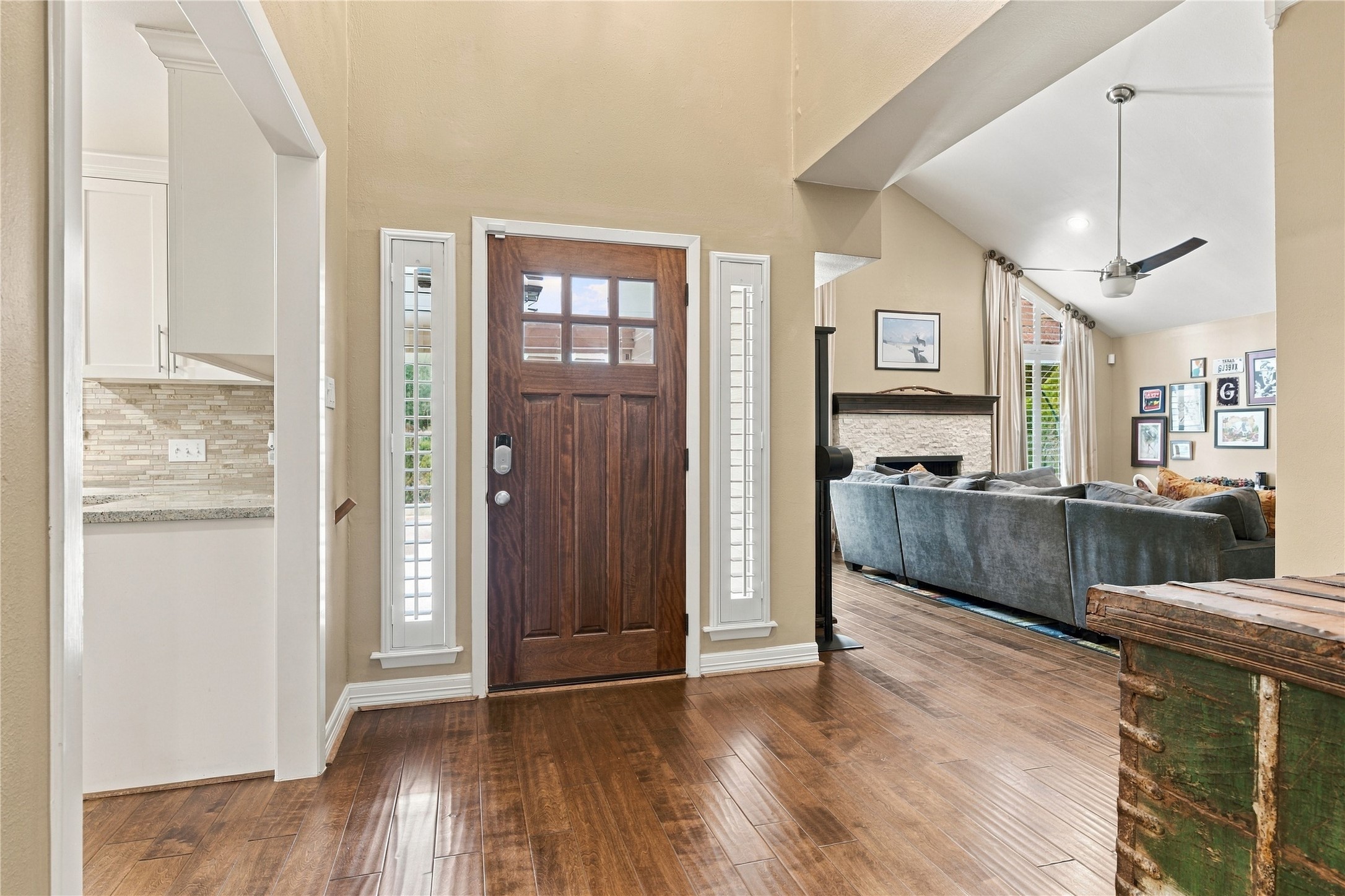 This welcoming foyer is draped in natural light through the plantation windows beside the wood door.