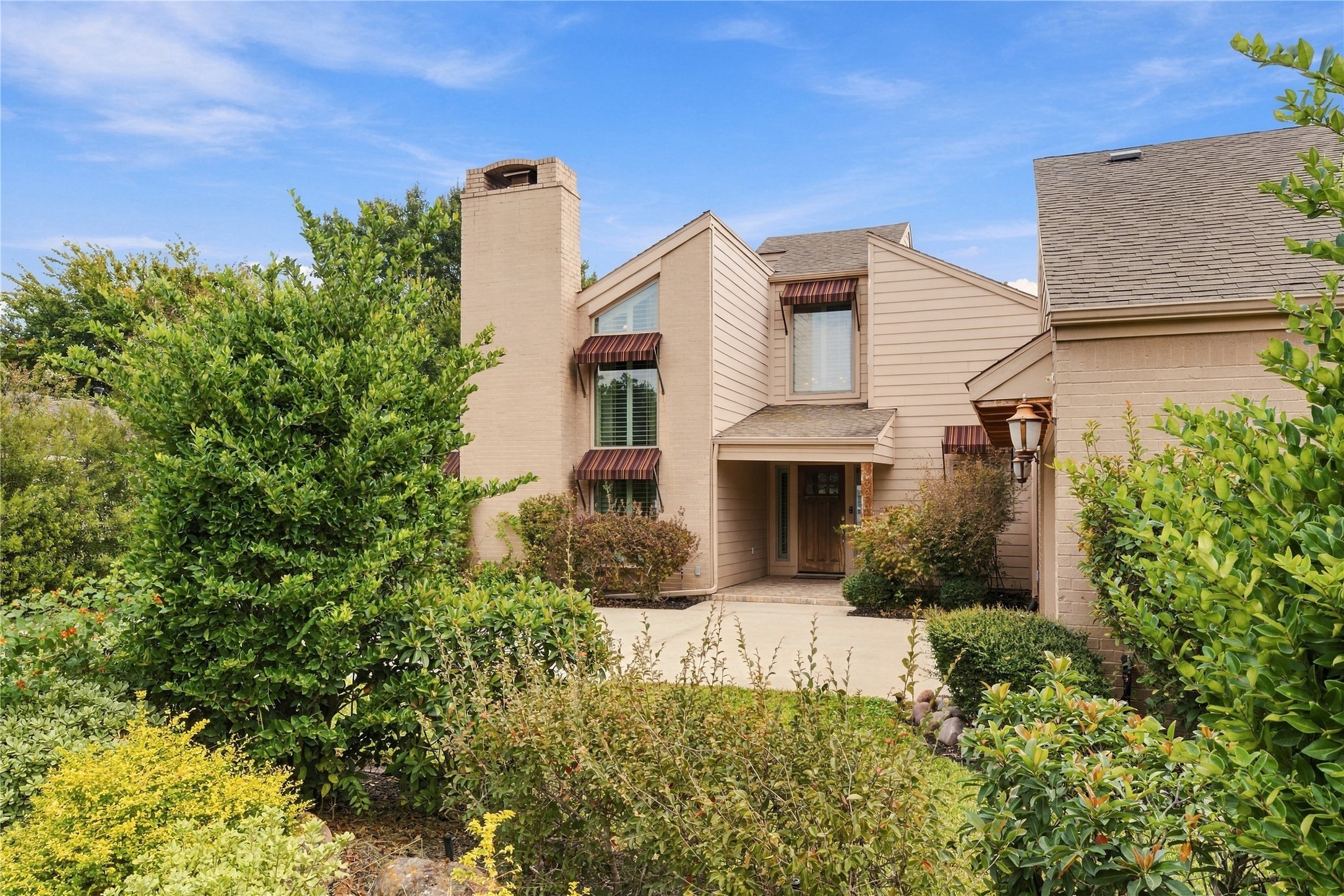 Mature shrubs & layered garden beds frame the approach to the front door, giving the entry a private, tucked-away feel from the street.