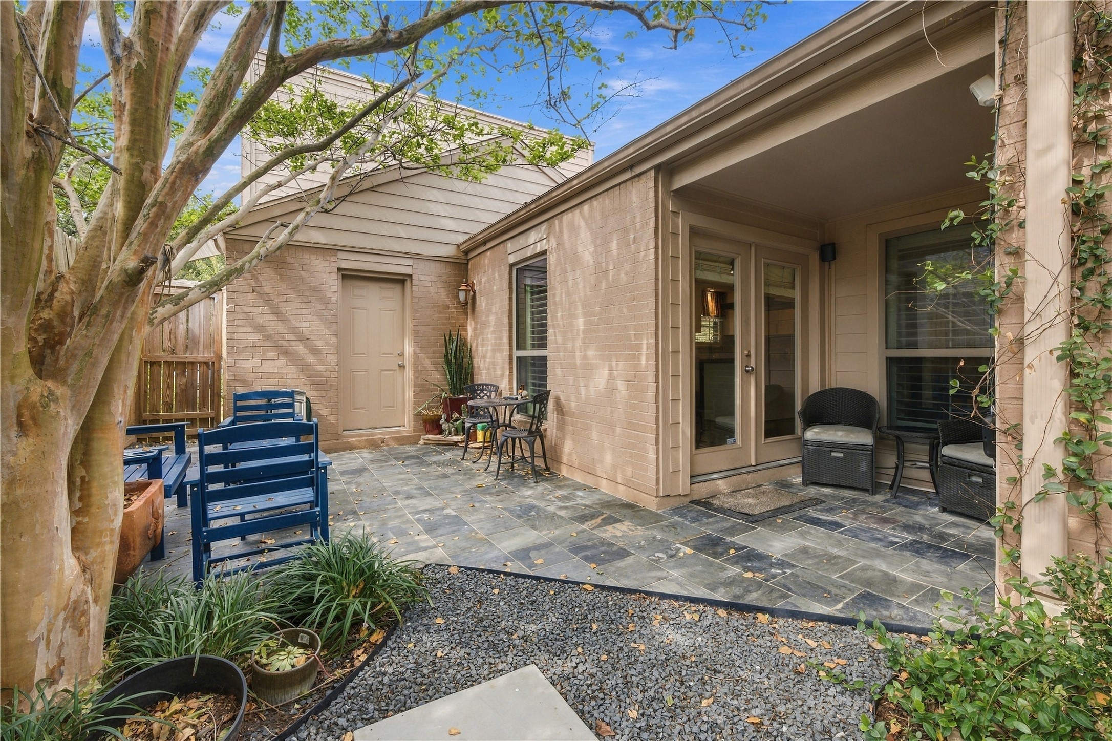 Stepping outside from the kitchen, a small covered patio opens to a paved outdoor seating space and travels back into a stunning outdoor retreat.