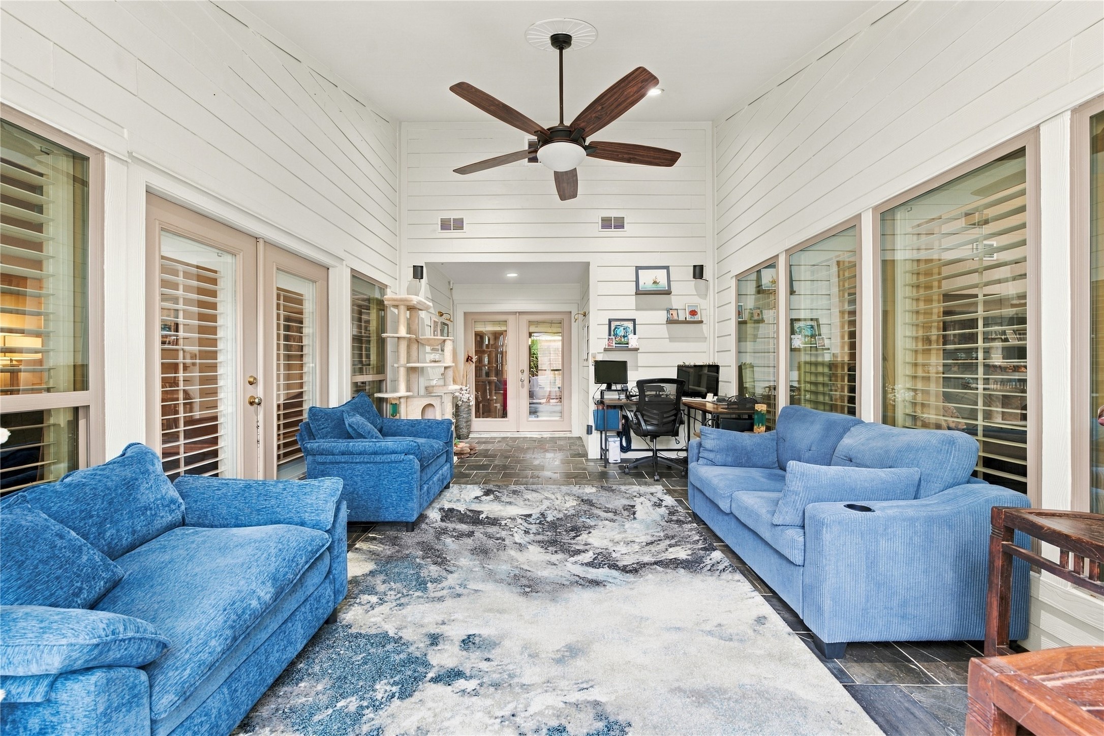 Relaxed, porch-like sunroom w/ ceiling fan & recessed lighting for year-round comfort, ideal for morning coffee, a reading nook, or a home office. French doors at the far end carry the flow into the rest of the home.