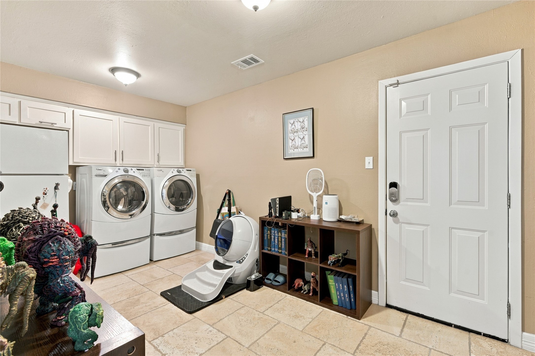 This spacious utility room is just steps off of the kitchen and seamlessly connects to the garage making unloading groceries a breeze.  The room also boasts additional storage space above the washer and dryer in addition to a dedicated space for an additional refrigerator.