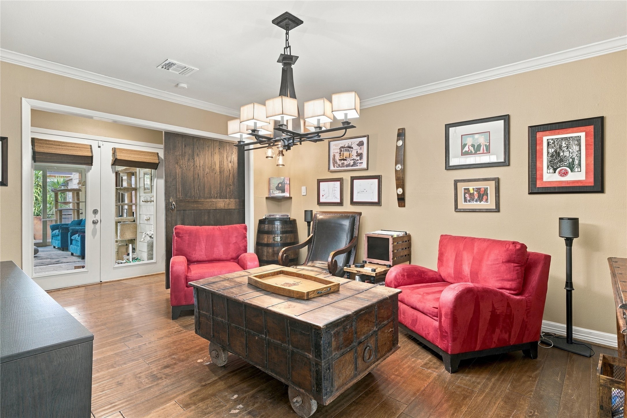 This warm and inviting formal dining room, currently used as a lounge/den, features a sliding wood barn door, crown molding & a modern iron chandelier.  Perfect for family gatherings or an additional seating space.