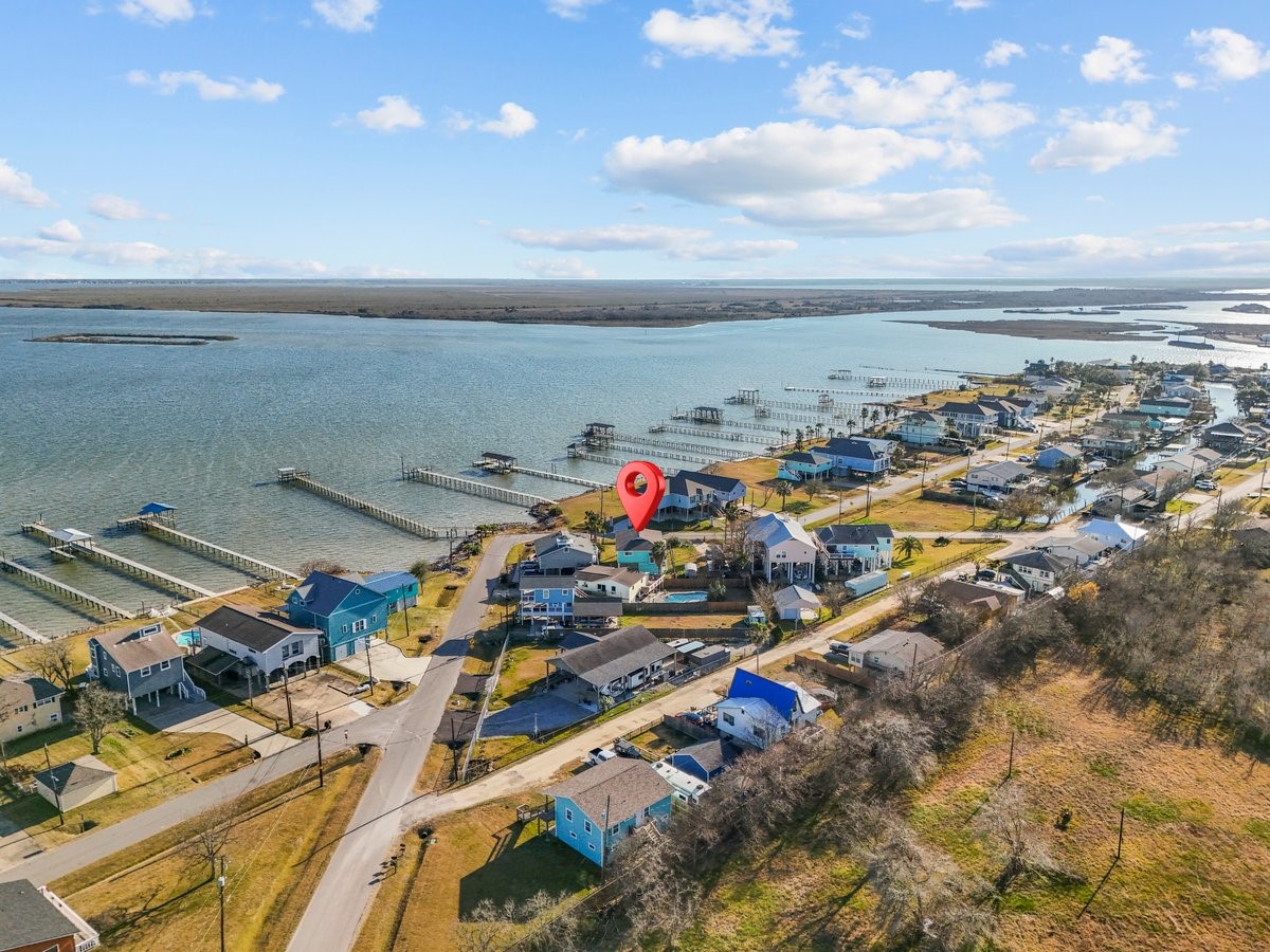 This photo showcases a charming coastal neighborhood with waterfront properties, docks, and scenic views of a bay. The area is marked by a pin, indicating a specific home, surrounded by well-maintained houses and lush greenery, perfect for those seeking a serene waterside lifestyle.