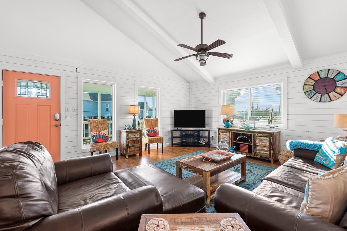 This cozy living room features a vaulted ceiling with exposed beams, a warm color palette, and plenty of natural light.