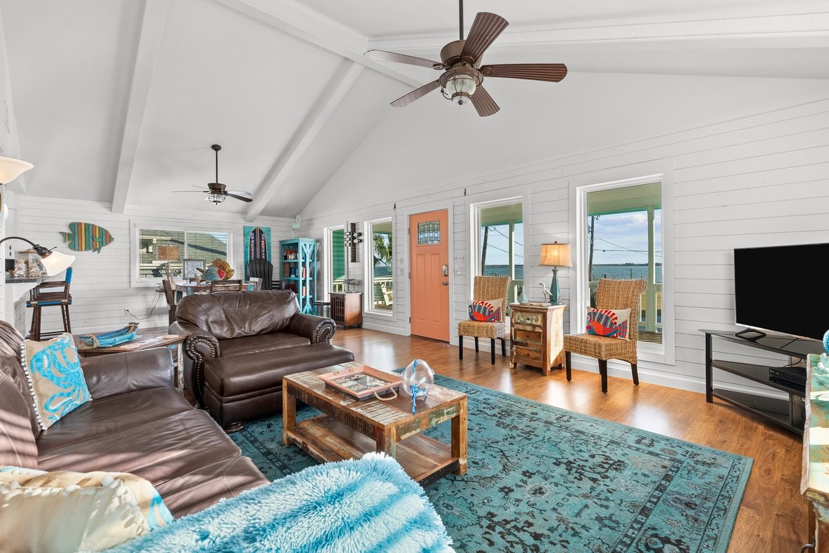 This inviting living room features vaulted ceilings and large windows offering plenty of natural light and scenic views. The open layout connects to a dining area, enhancing the sense of space and comfort. This inviting living room features vaulted ceilings and large windows offering plenty of natural light and scenic views. The open layout connects to a dining area, enhancing the sense of space and comfort.